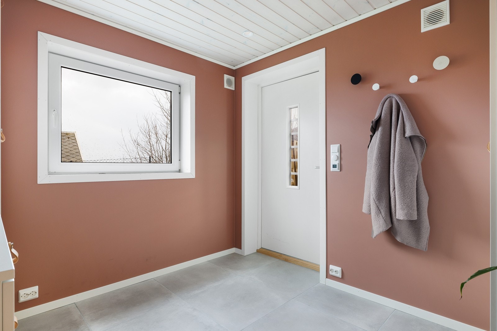 Inngangsparti med flislagt gulv og vindu som gir naturlig lys. Galleribilde