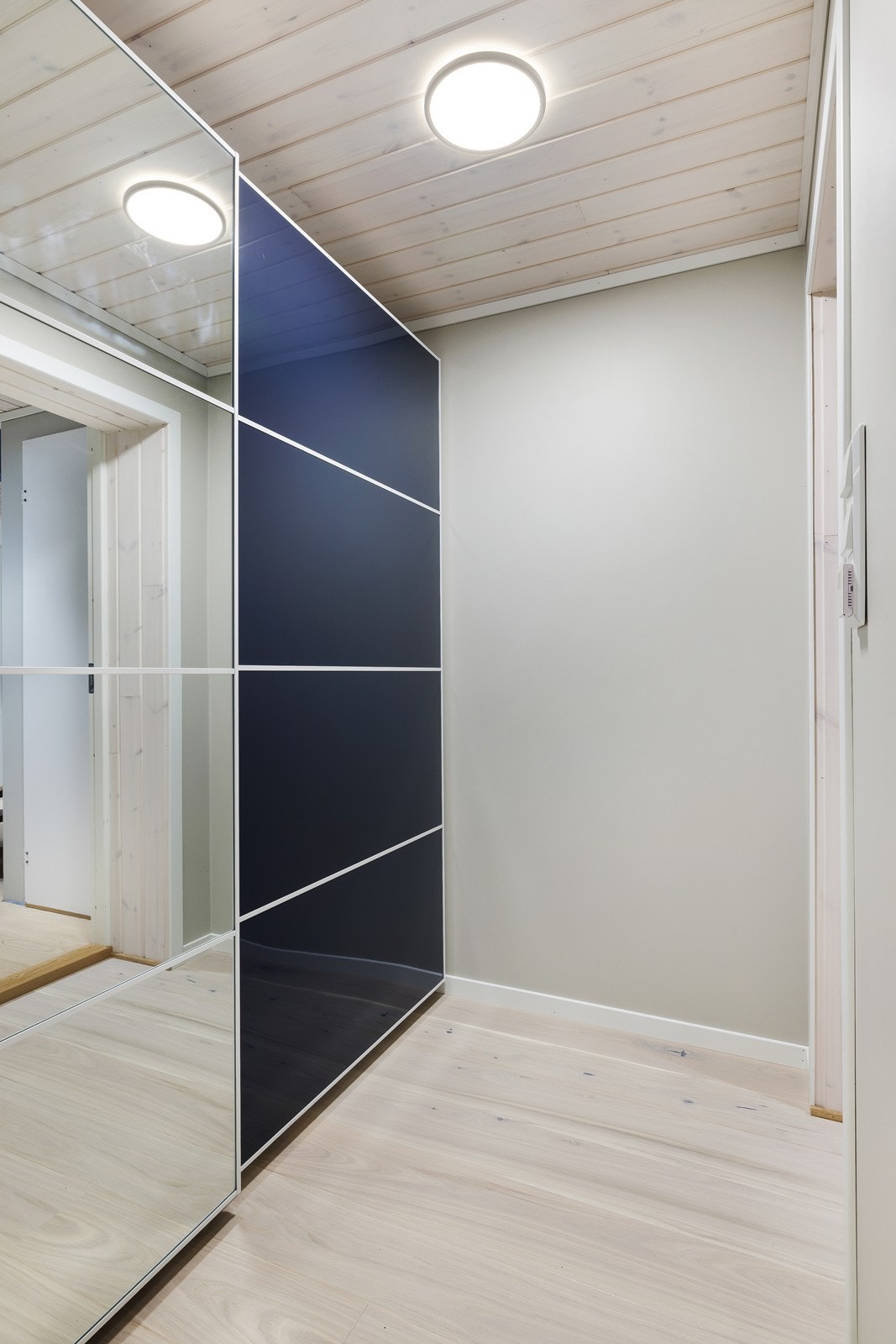 Garderobeløsning med skyvedører gir effektiv oppbevaring i entréen. Lyse tregulv og panel i himling skaper et helhetlig uttrykk. Galleribilde