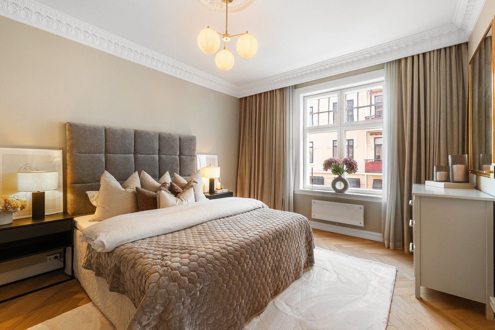 Et eksklusivt og romslig soverom med høy himling og klassisk stukkatur og rosett som skaper en elegant ramme rundt rommet. Galleribilde