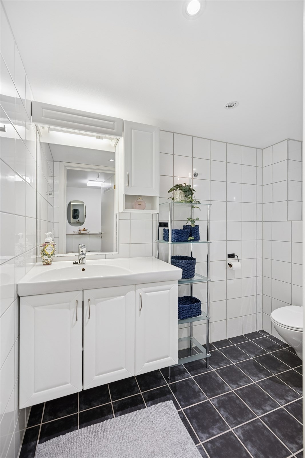 Badet er helfliset med mørke gulvfliser og lyse veggfliser. Galleribilde