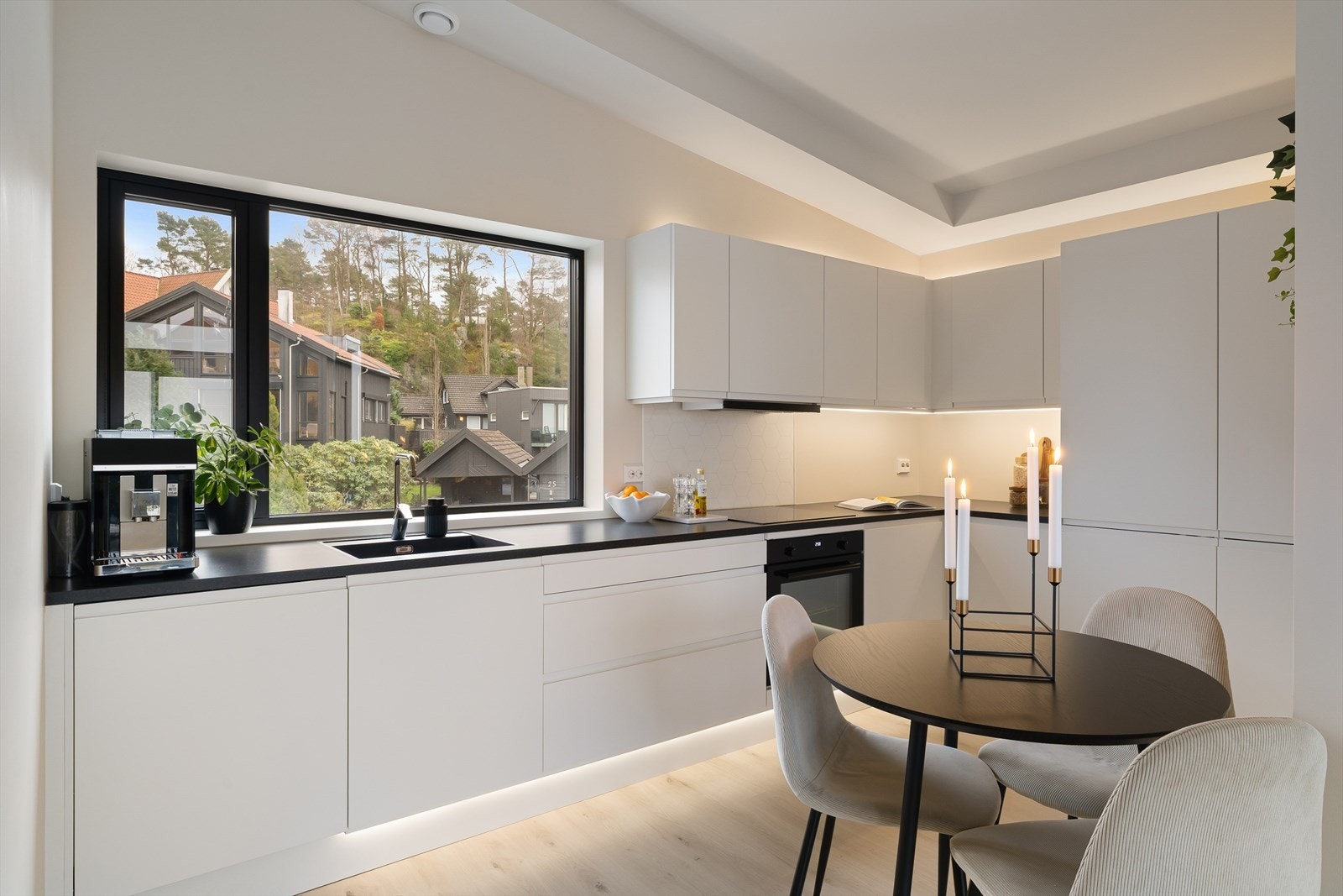 Flott og moderne kjøkken med pen kjøkkeninnredning i hvit utførelse og integrerte hvitevarer. Galleribilde