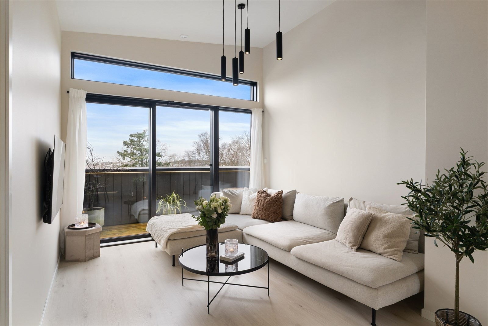 Leilighetens stue fremstår som lys og trivelig med store vindusflater som slipper inn mye naturlig lys som sammen med den ekstra takhøyden er med på å skape en god romfølelse og atmosfære. Galleribilde