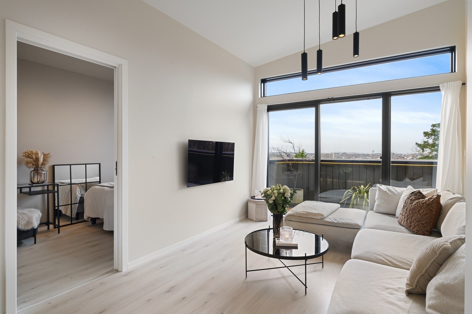 Leilighetens stue fremstår som lys og trivelig med store vindusflater som slipper inn mye naturlig lys som sammen med den ekstra takhøyden er med på å skape en god romfølelse og atmosfære. Galleribilde