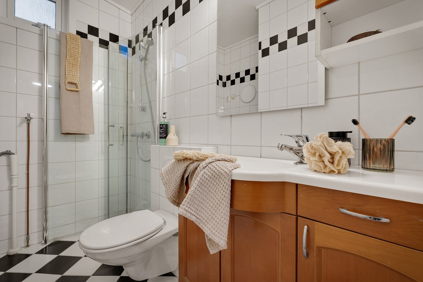 Dusjhjørne, vegghengt toalett og servant med speil over Galleribilde