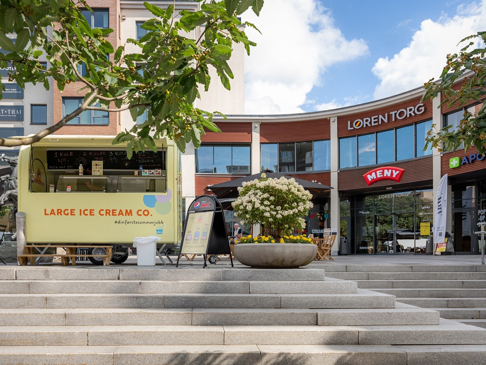 Løren torg med flere butikker som Meny, apotek og uteservering på sommerstid. Galleribilde