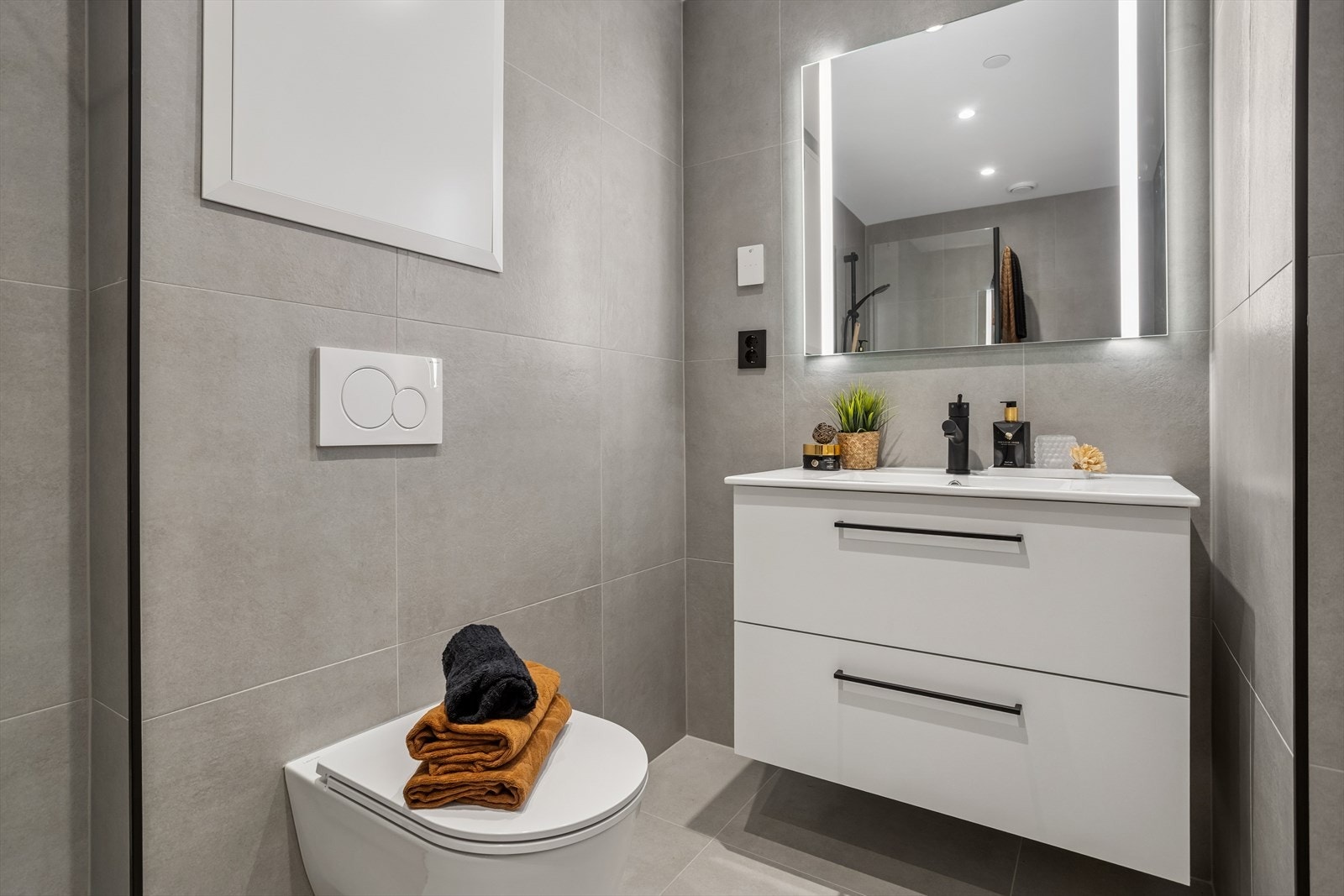 Veggene er flislagt, himlingen malt. Innredningen består av heldekkende servant med to skuffer i hvite fronter, speil med lys og dobbel stikkontakt. Galleribilde