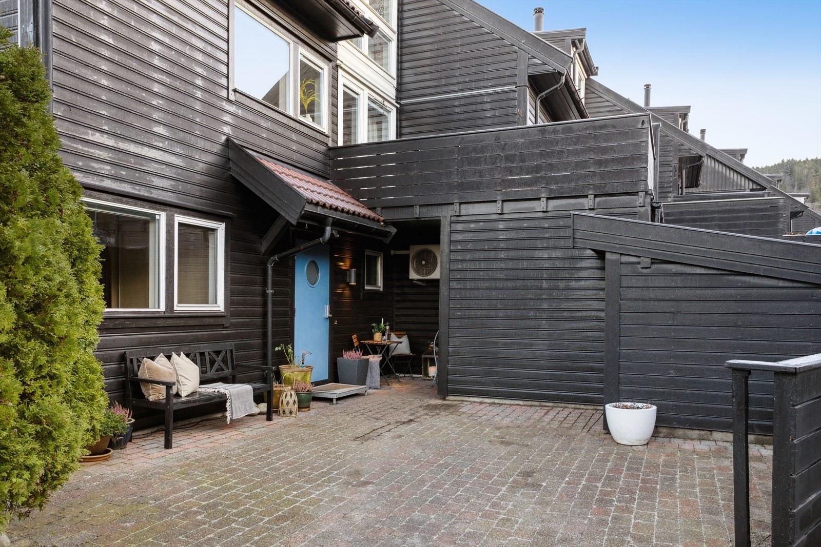 Stor gårdsplass ved inngangspartiet. Her er det 2 uteboder og ellers parkeringsplass med lademulighet. Galleribilde