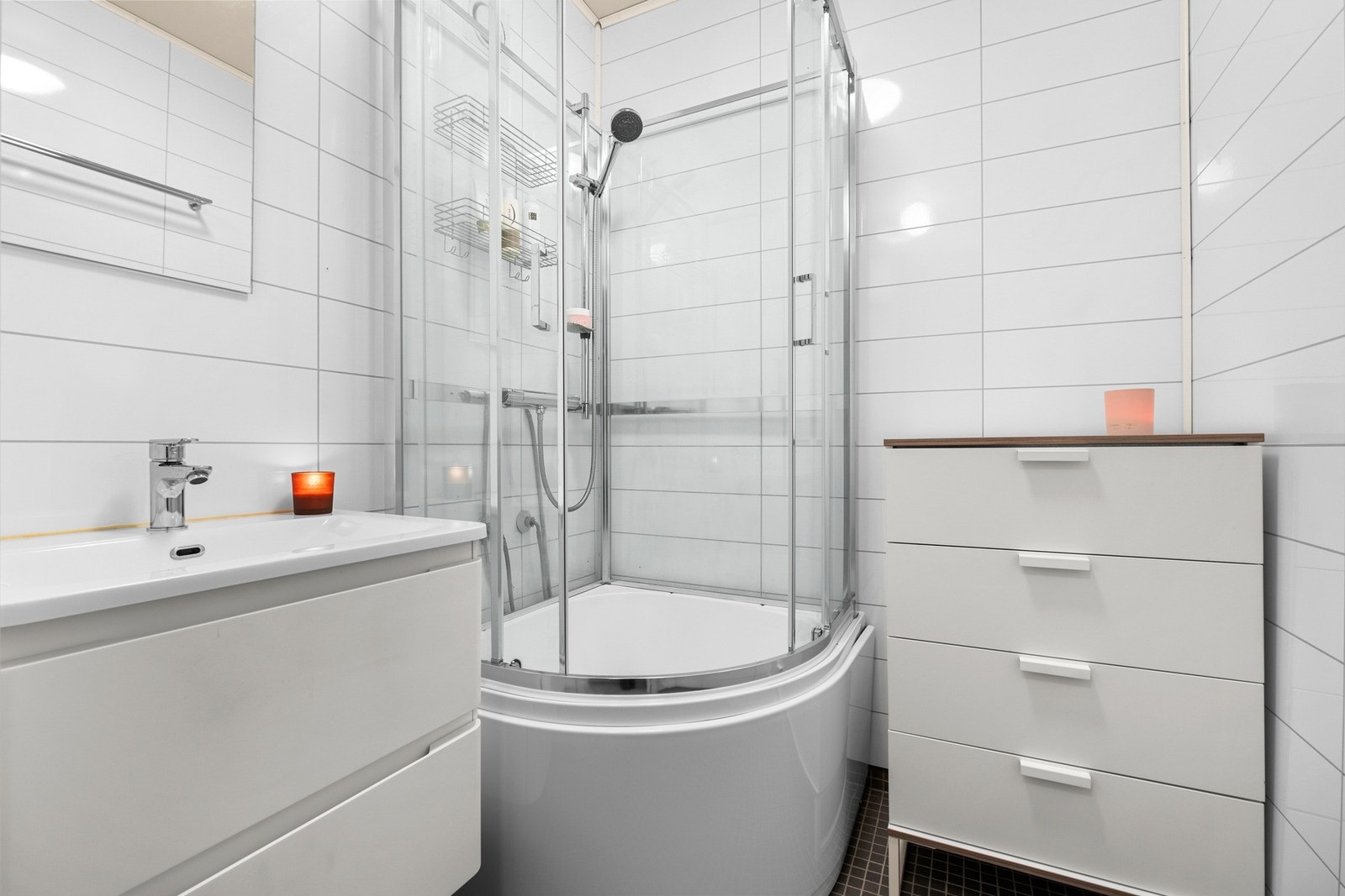 Pent flislagt bad som er utstyrt med gulvvarme, veggmontert servantinnredning og dusjkar Galleribilde