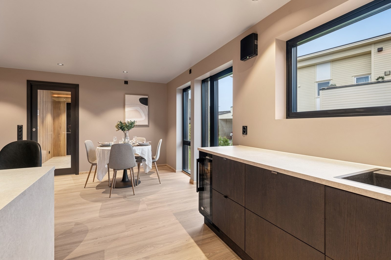 Fargepaletten i boligen er nøytral med beige, hvitt, brunt og naturtoner, kombinert med svarte detaljer for kontrast. Galleribilde