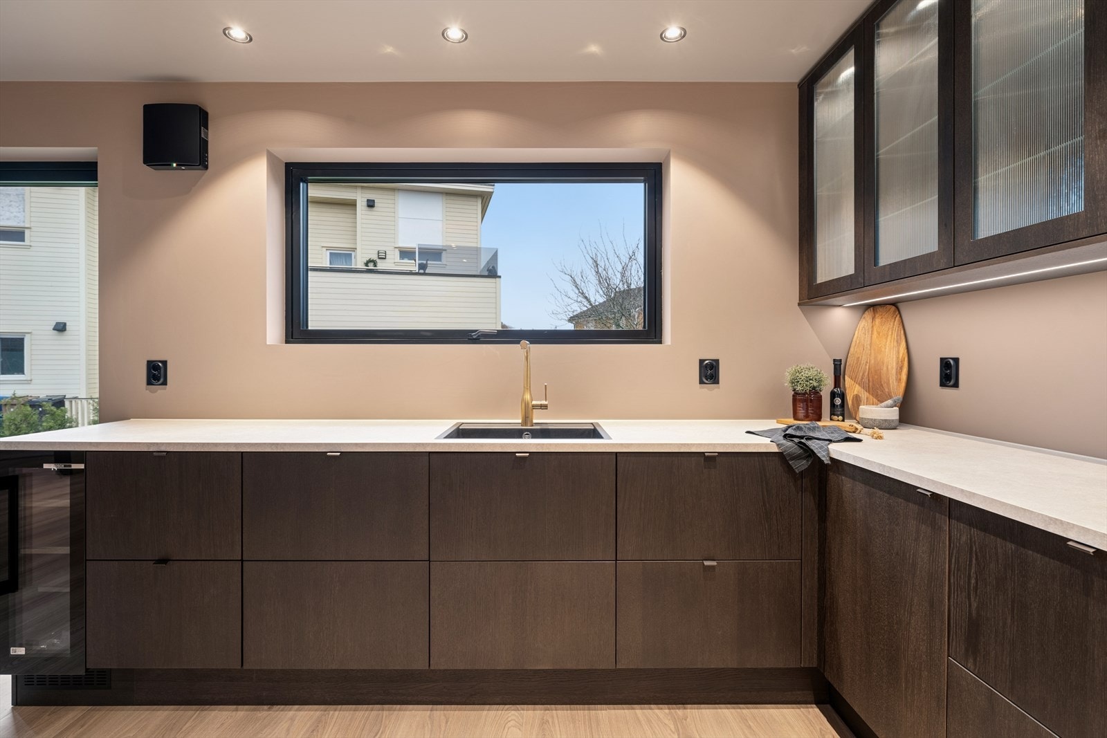 Kombinasjon av mørke og lyse overflater samt overskap med glass gir et sofistikert preg. Galleribilde