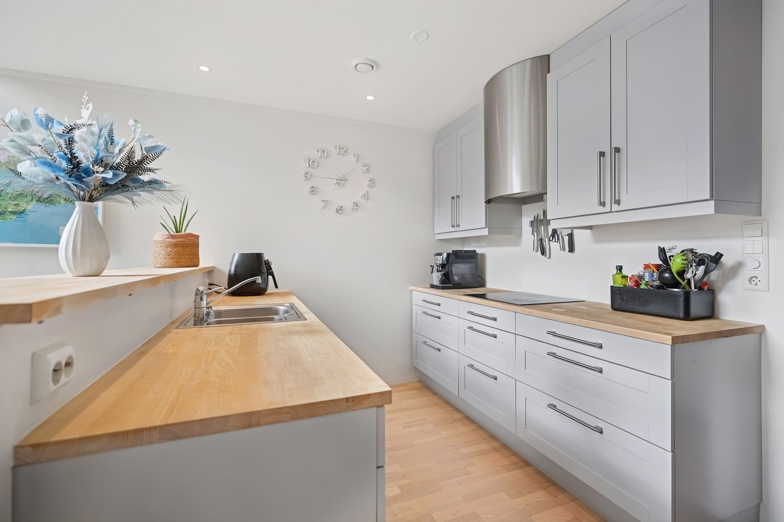 Kjøkkenet har en pen og tidløs innredning med grå, profilerte fronter og heltre benkeplate med nedfelt kjøkkenkum. Galleribilde