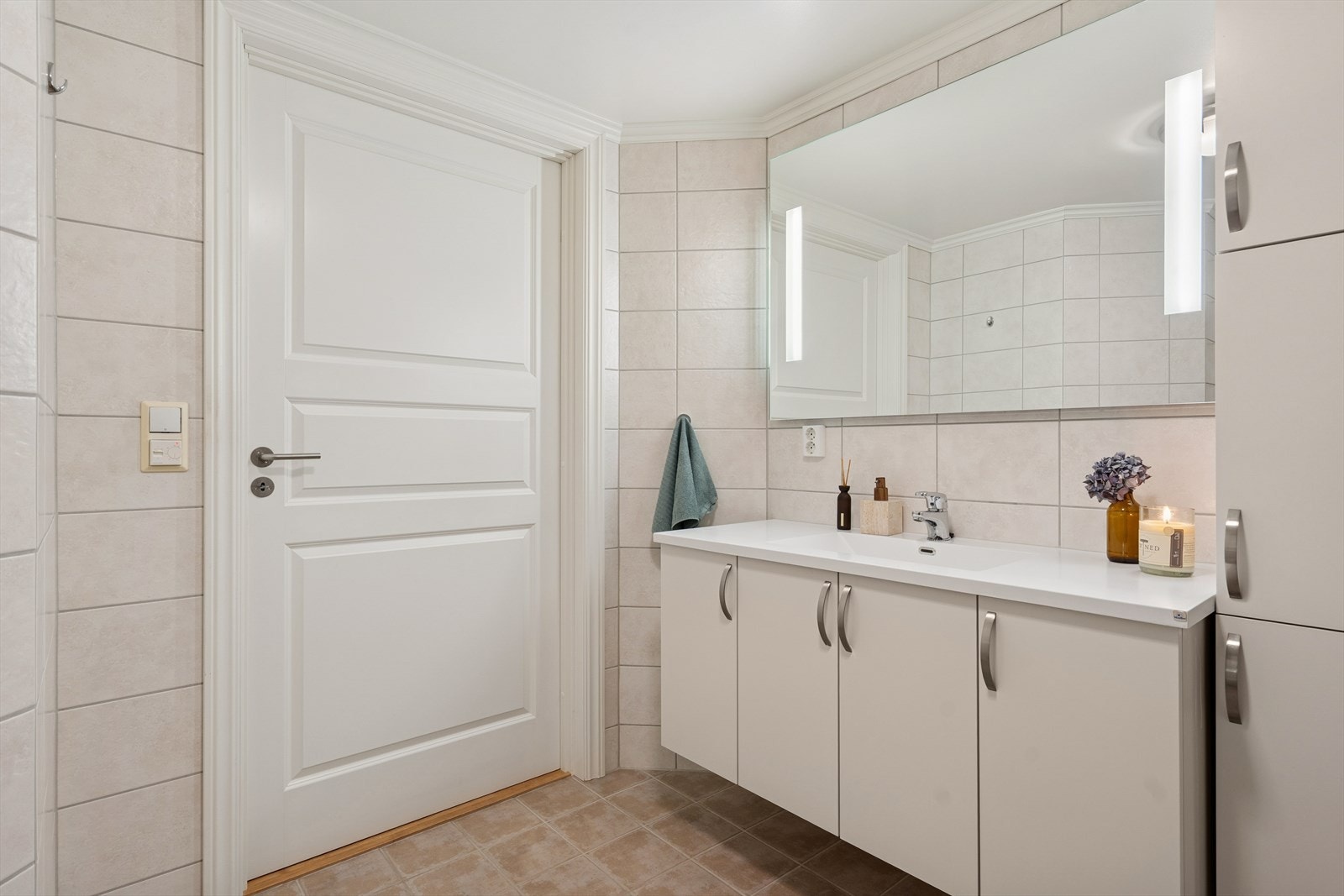 Badet har vegghengt toalett, servant med underskap, speil med belysning og opplegg for vaskemaskin. Galleribilde