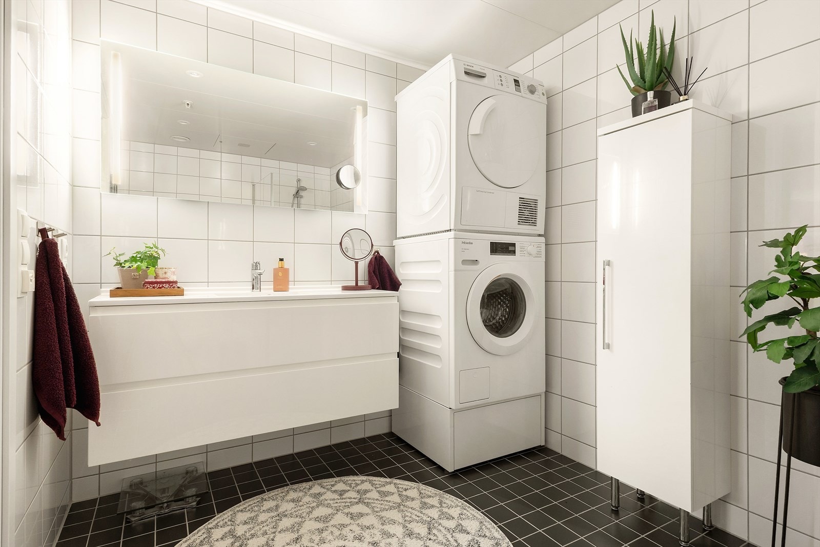 Badet er stort og har innredning med slette fronter og nedfelt servant, høyskap, veggmontert toalett, dusjhjørne med dører og opplegg for vaskemaskin. Galleribilde