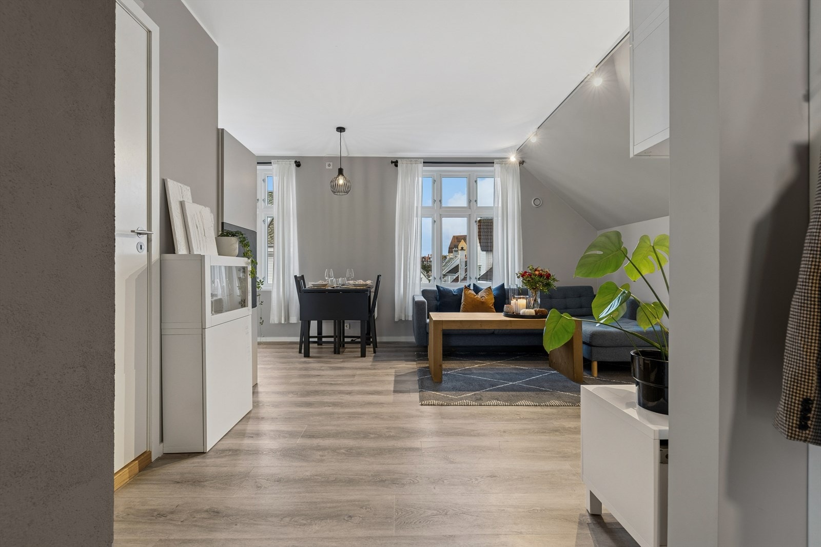 Stue og kjøkken ligger i åpen løsning. Her har man store vindusflater som gir rikelig med naturlig lys og slette, malte overflater med listefrie overganger til tak som gir et moderne og stilrent uttrykk. Galleribilde