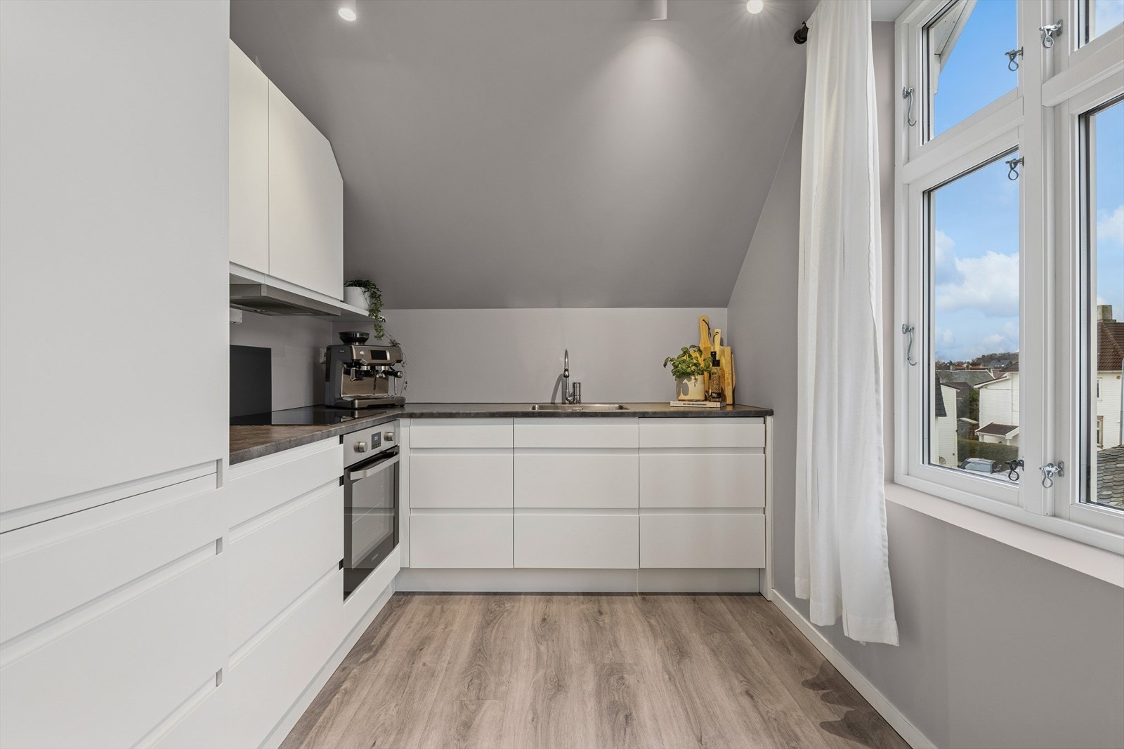 Kjøkkenet ble byttet i 2017 og er innredet med hvite, slette fronter og grå benkeplate i laminat. Her har man godt med skap- og skuffeplass, samt gode arbeidsflater på benk. Galleribilde