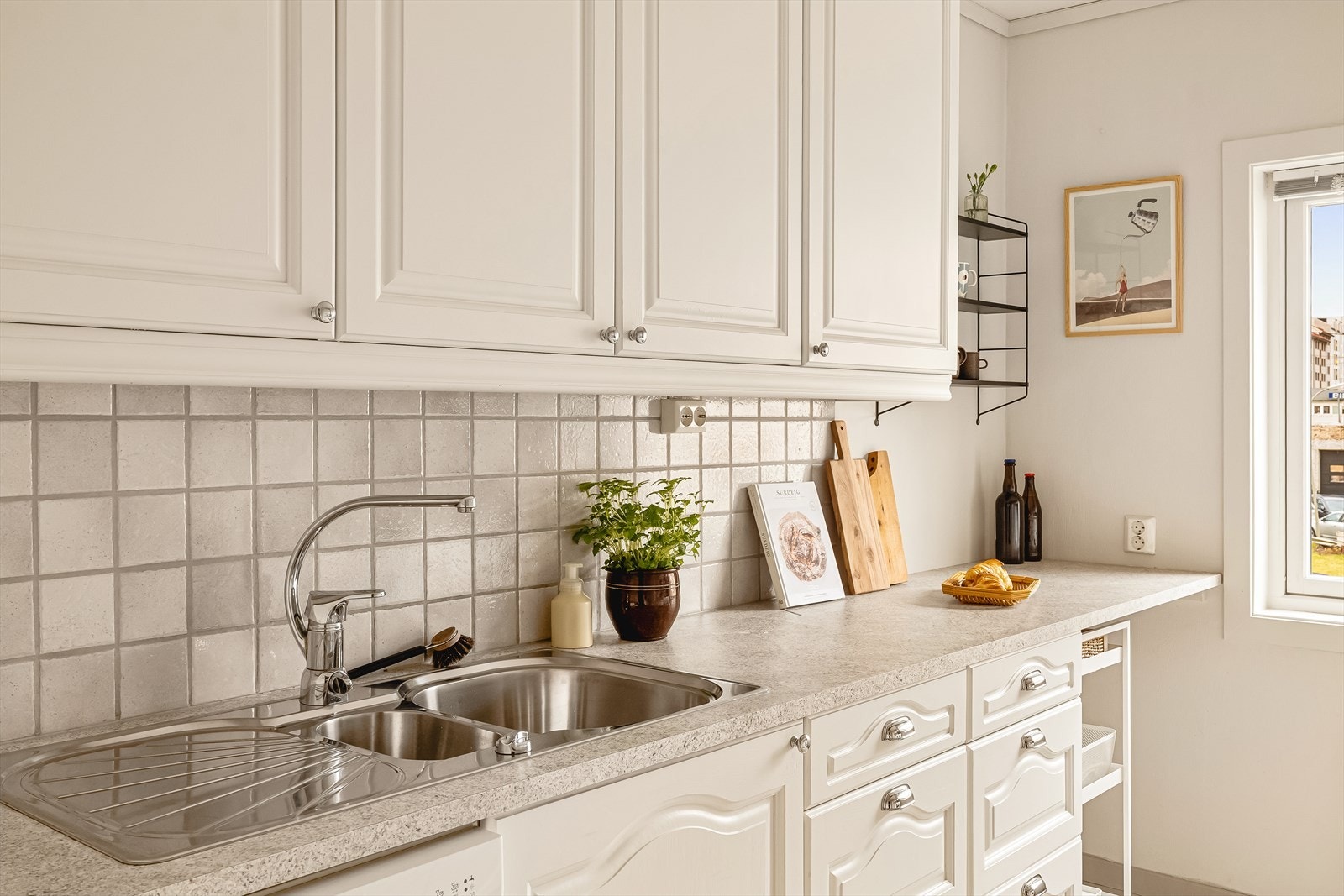 Kjøkkeninnredningen har profilerte hvitmalte fronter i eik, laminat benkeplate, stålvask, ventilator med avtrekk ut av bygget og opplegg for vaskemaskin. Galleribilde