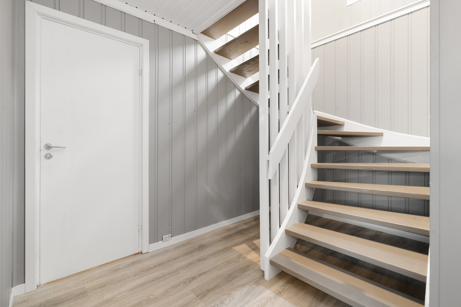 Romslig gang i underetasjen, med malt tretrapp til hovedetasjen. Galleribilde