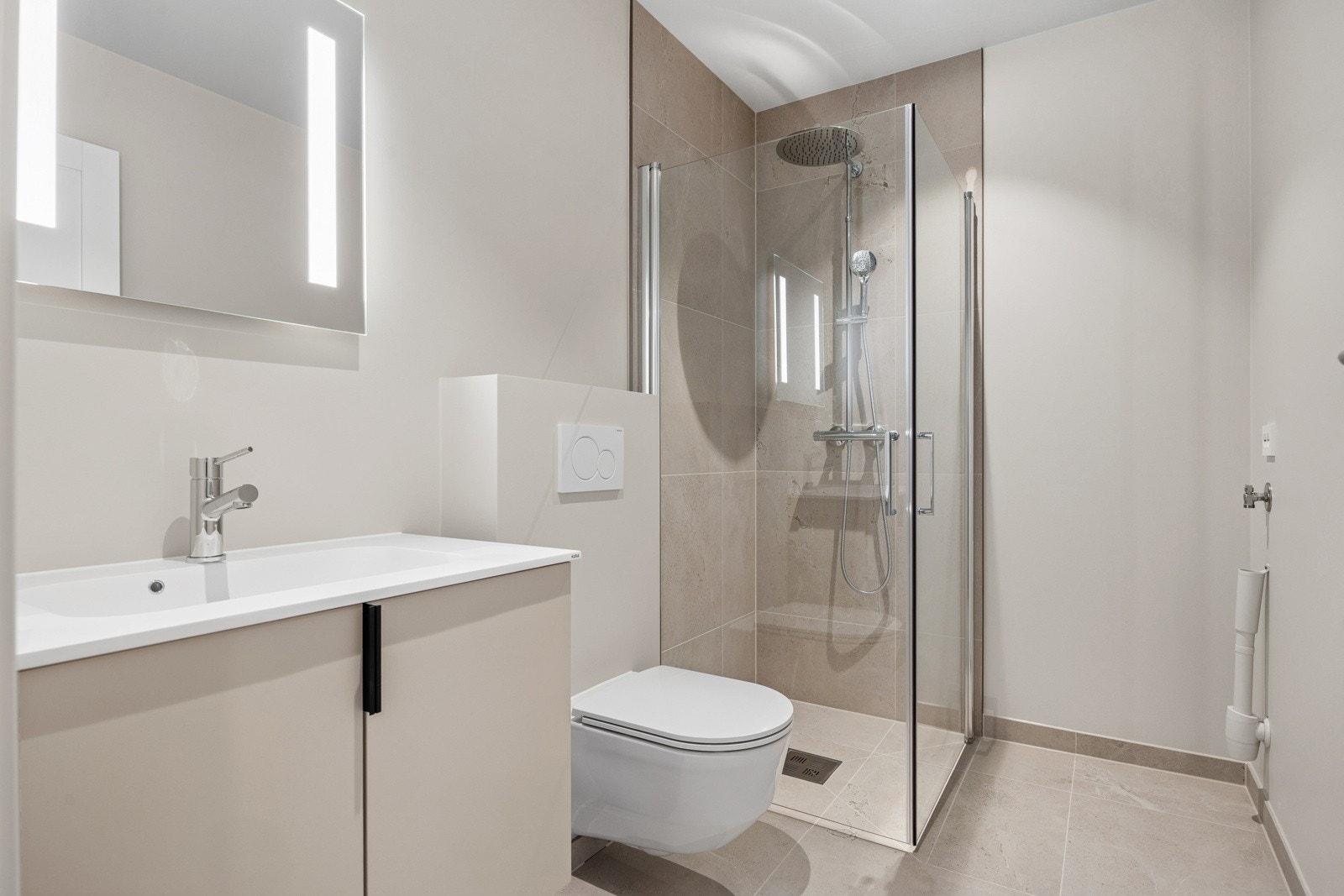 Badet har malte overflater, flis på gulv og flislagte vegger i dusjsonen, og er innredet med dusjhjørne, toalett og servant. Galleribilde