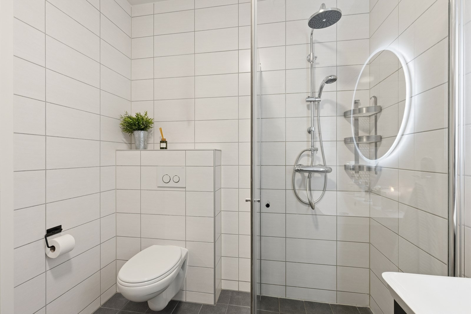 Bad/vaskerom utstyrt med dusjhjørne med glassdører og vegghengt toalett. Galleribilde