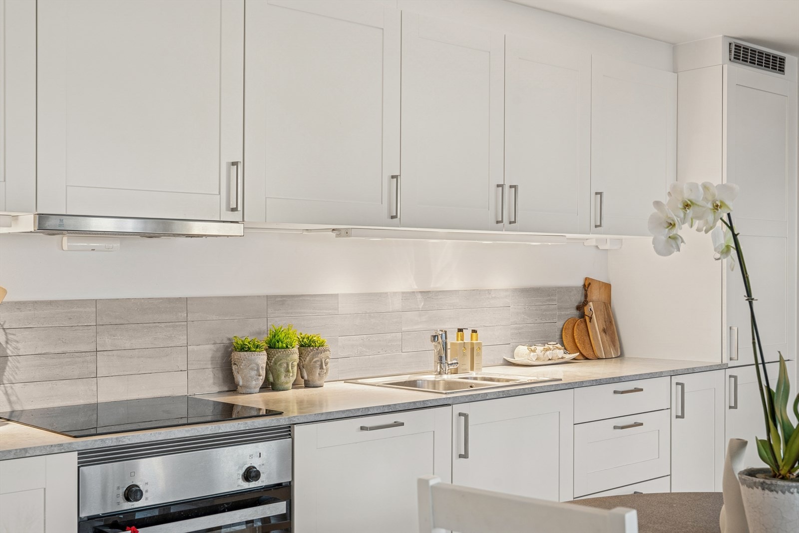 Kjøkkenet er innredet med hvite, profilerte fronter og grå benkeplate i laminat. Et godt utnyttet kjøkken hvor man har godt med skap- og skuffeplass. Galleribilde