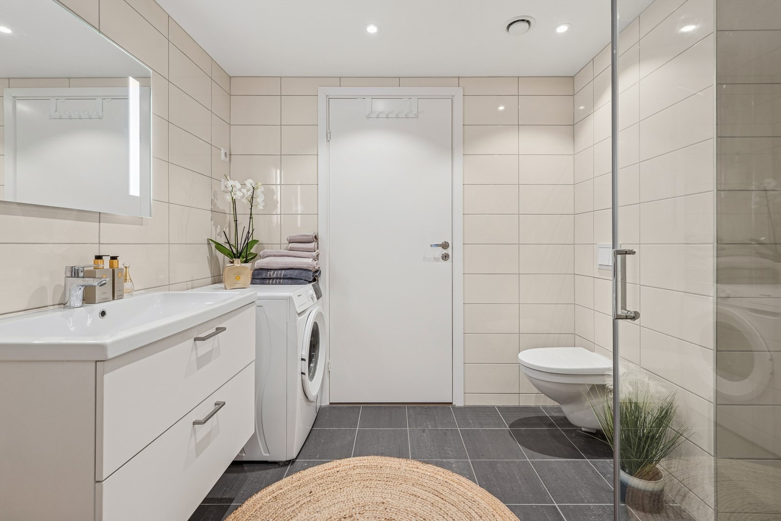 Badet er tidløst innredet med grå fliser på gulvet og lyse fliser på vegg. I gulvet har man også varmekabler for ekstra komfort. Galleribilde