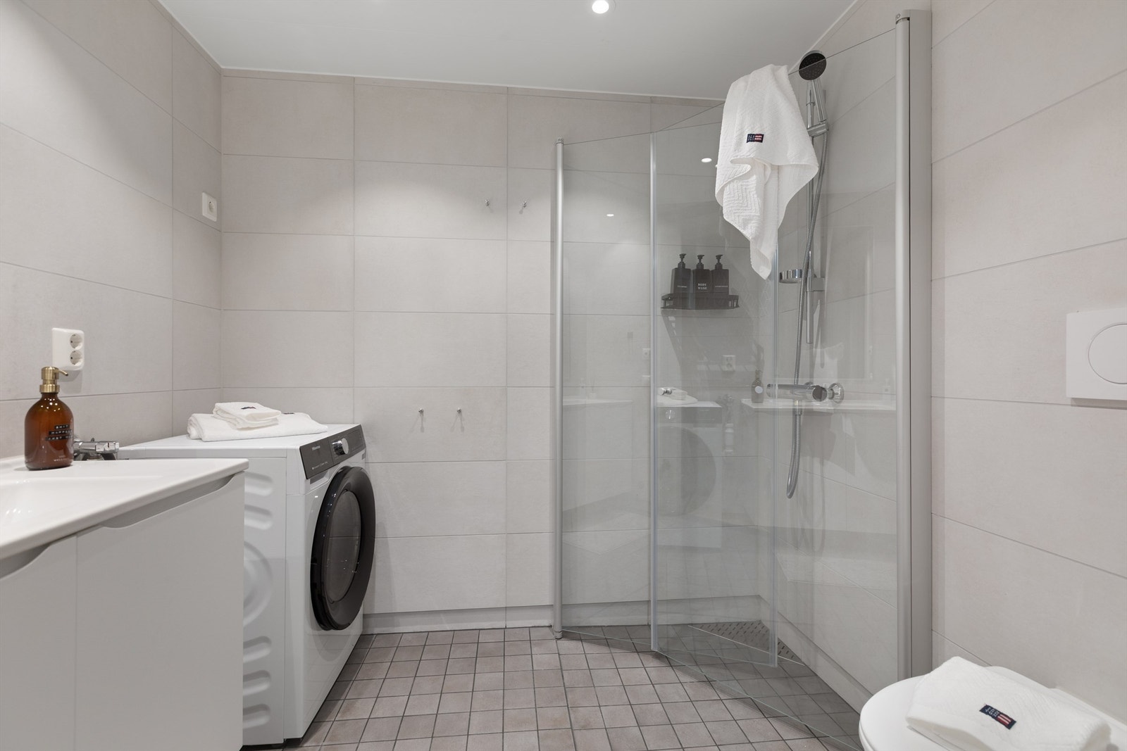 Bad med flislagt gulv med gulvvarme, flislagte vegger og vegghengt toalett. Galleribilde