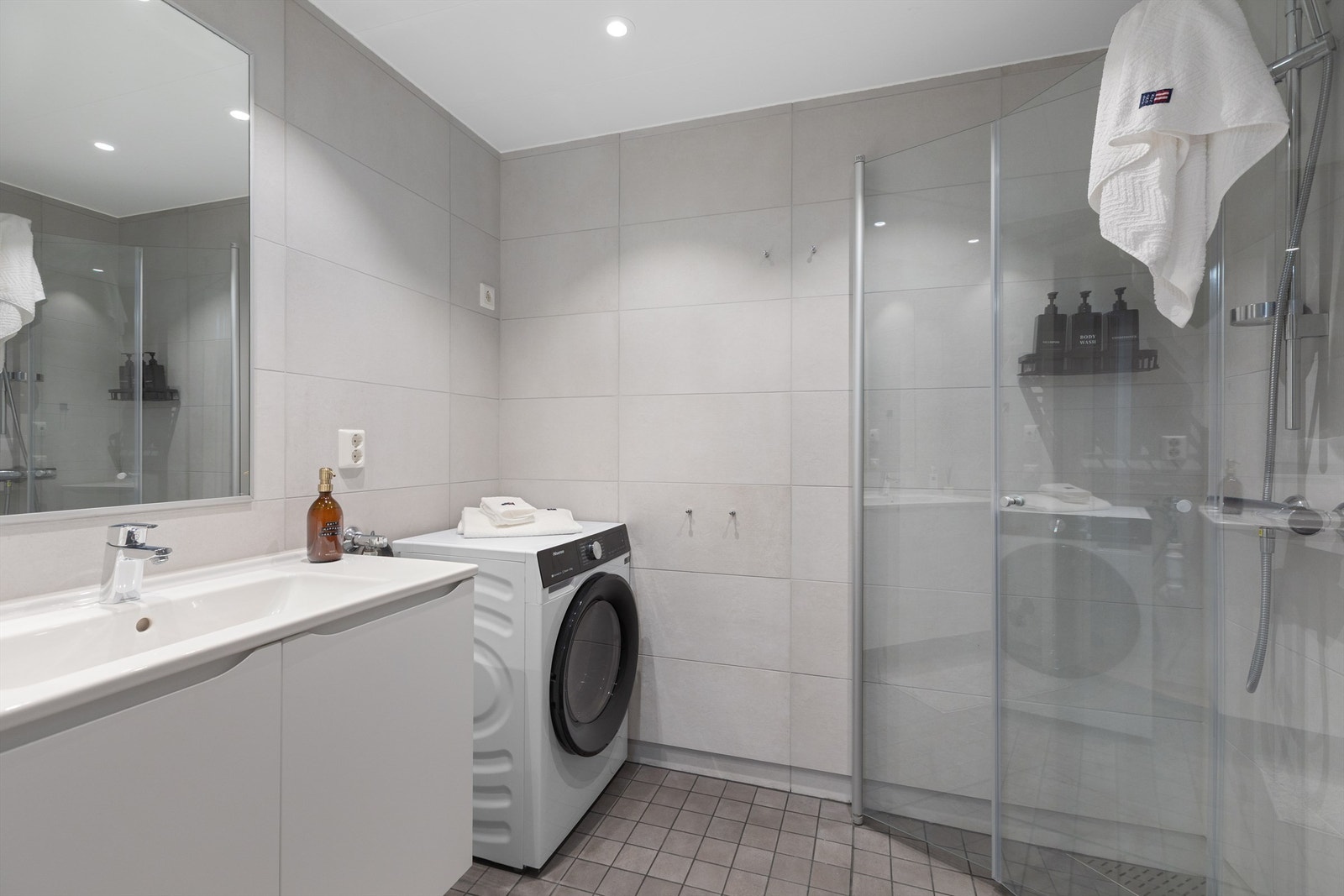 Badet har vegghengt servantinnredning og ovenpåliggende servant med ett-greps armatur. Dusjhjørne med dører. Galleribilde