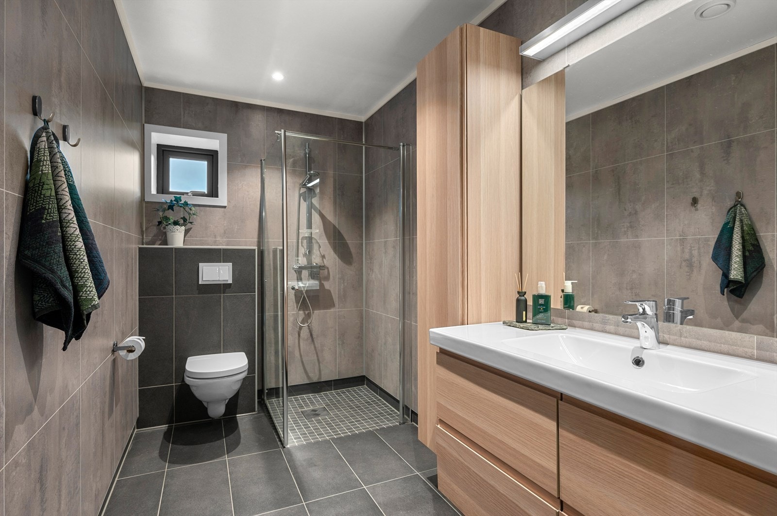 Badet i underetasjen er også av romslig størrelse på 9,5 m² med dusj, vegghengt toalett og servant i skap. Galleribilde