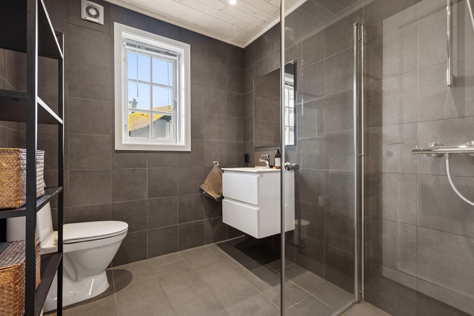 Badet har flislagt gulv med elektriske varmekabler og ligger romslig til i første etasje. Praktisk løsning som gjør det enkelt å gå rett inn for både små og store, mens lek og kos pågår ute. Galleribilde