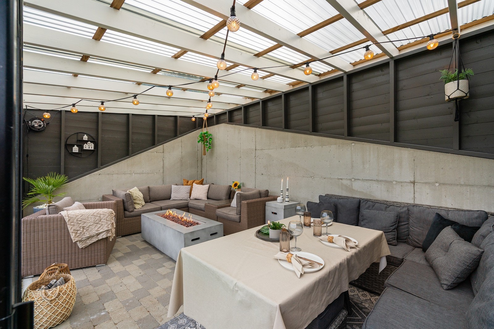 Et gjennomført uterom med belegningsstein på gulv og rustikke vegger i mur og tre. Galleribilde