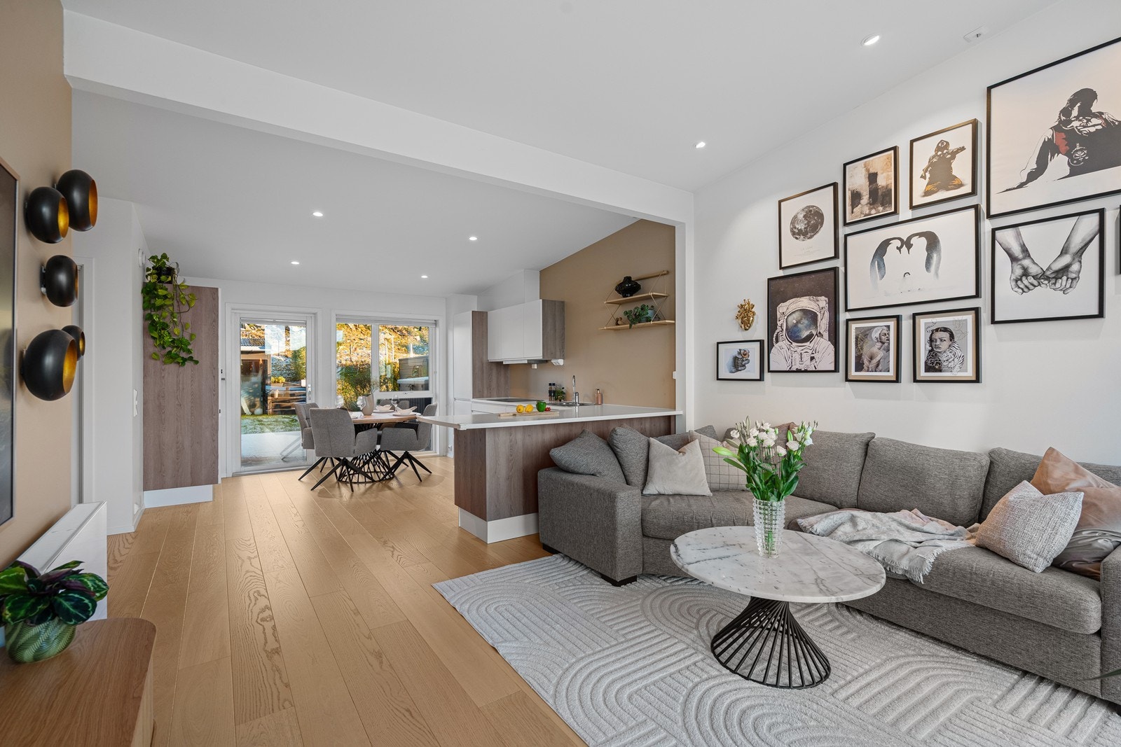 Moderne kjøkken i hvitt med stilrene treverkdetaljer. Spiseplass og utgang til terrasse og hage. Galleribilde