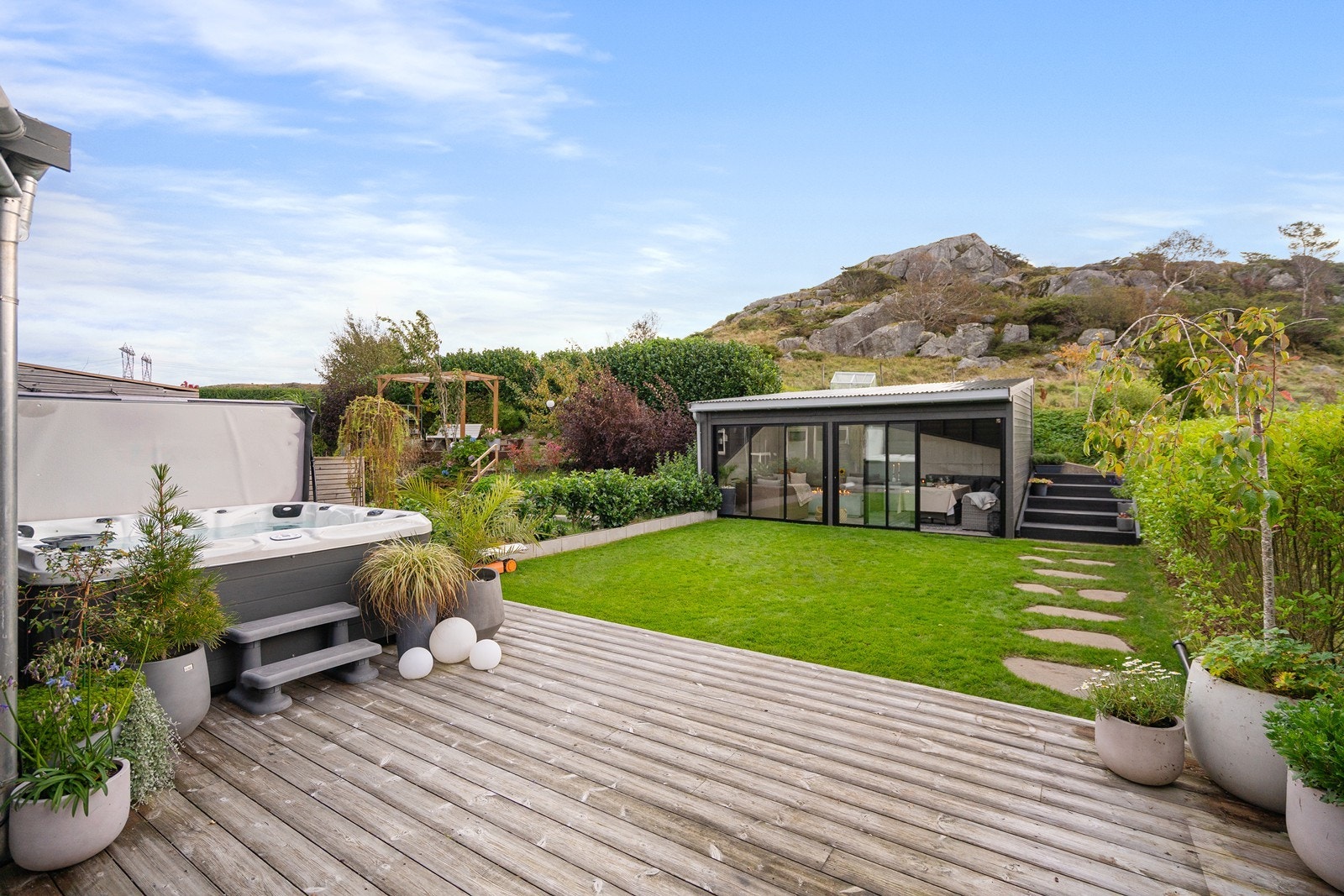 Velstelt hage med hellelagt sti som leder ned til eiendommens hyggelige hagestue (ikke byggemeldt og godkjent). Galleribilde