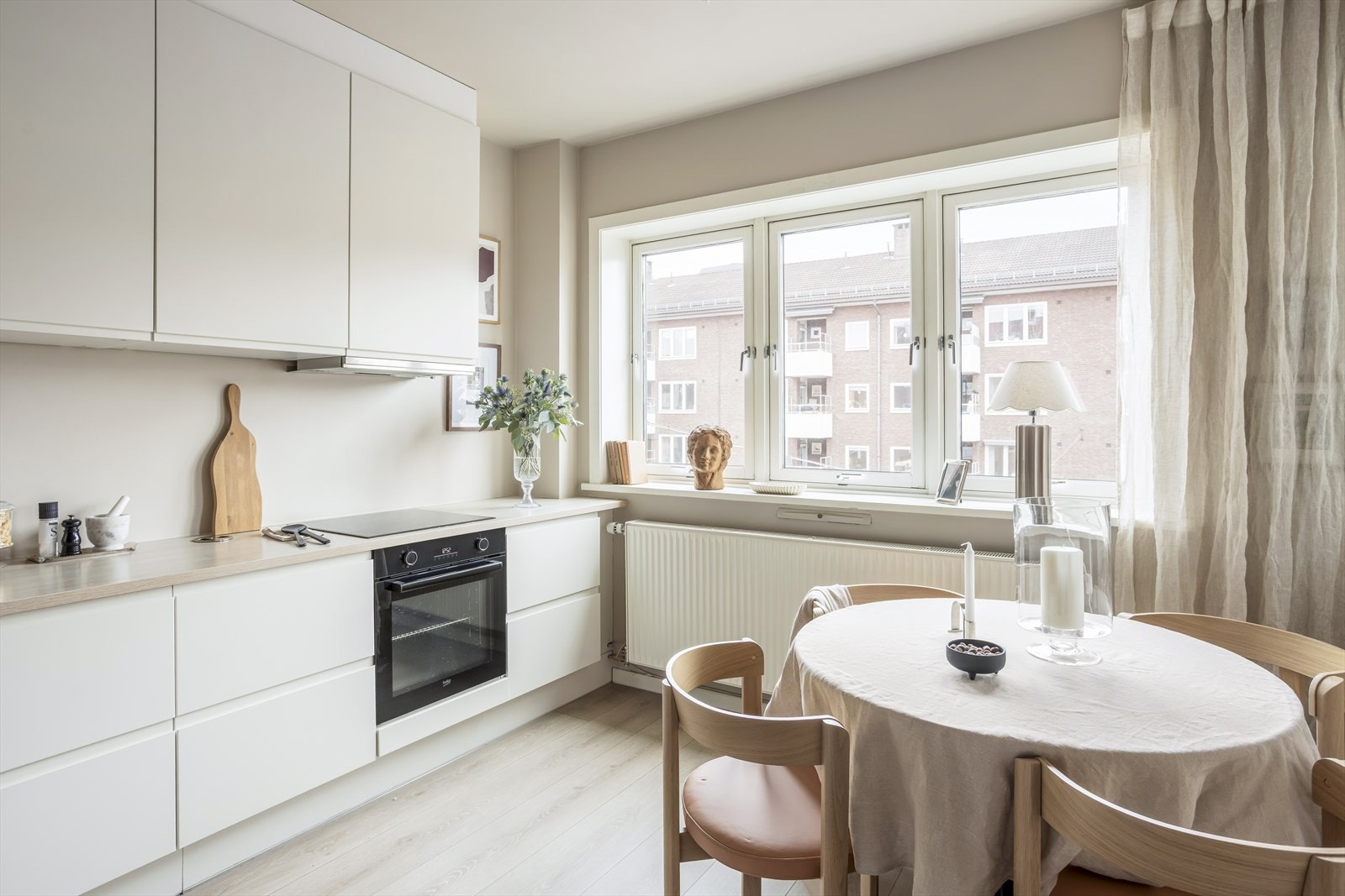 Kjøkkeninnredningen har glatte, folierte fronter som gir et elegant og rent uttrykk, mens laminat benkeplaten med underlimt komposittkum tilfører både kvalitet og brukervennlighet. Galleribilde