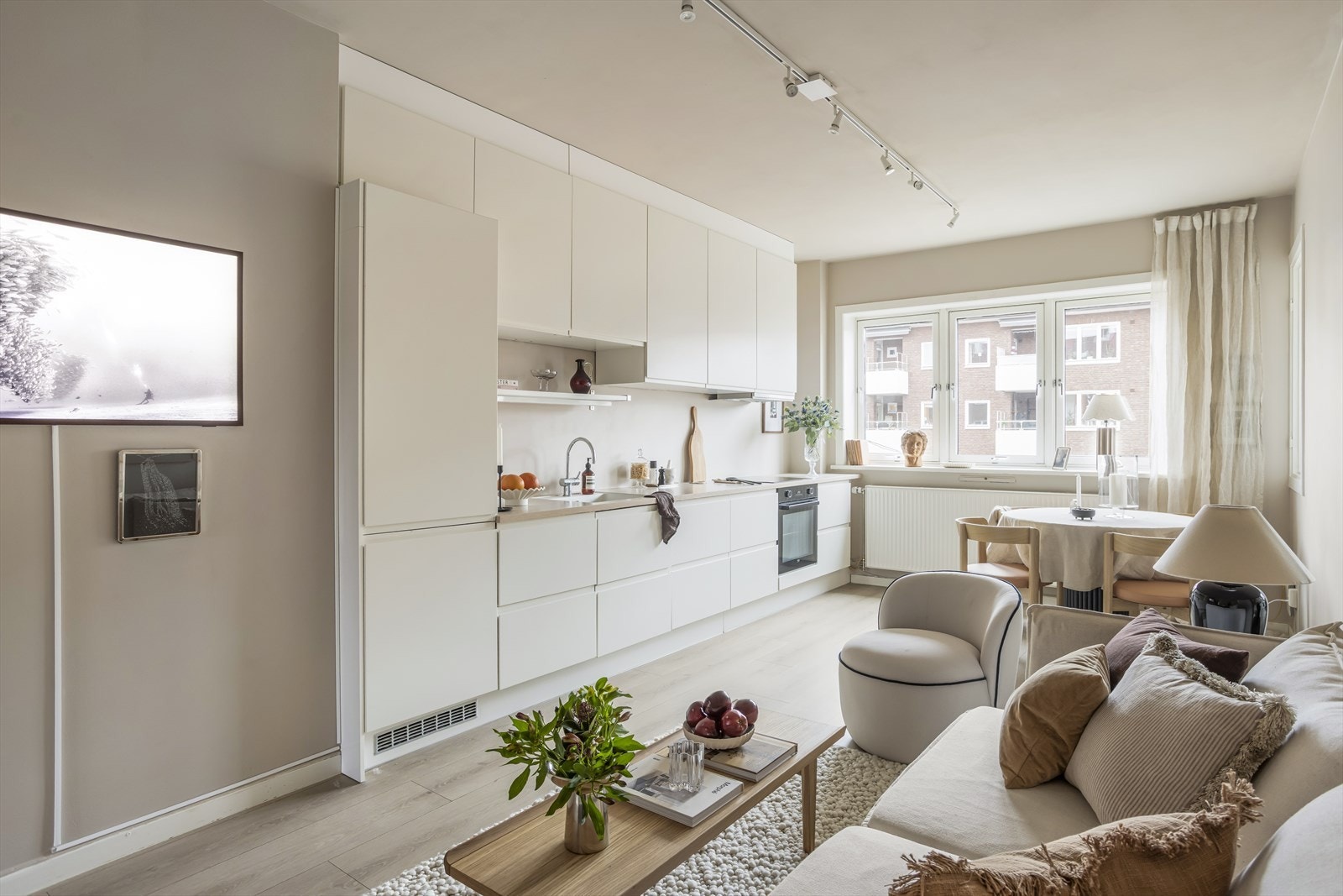 Stilren stue- og kjøkkenløsning i åpen løsning som er med på å danne en romslig og sosial atmosfære. Galleribilde