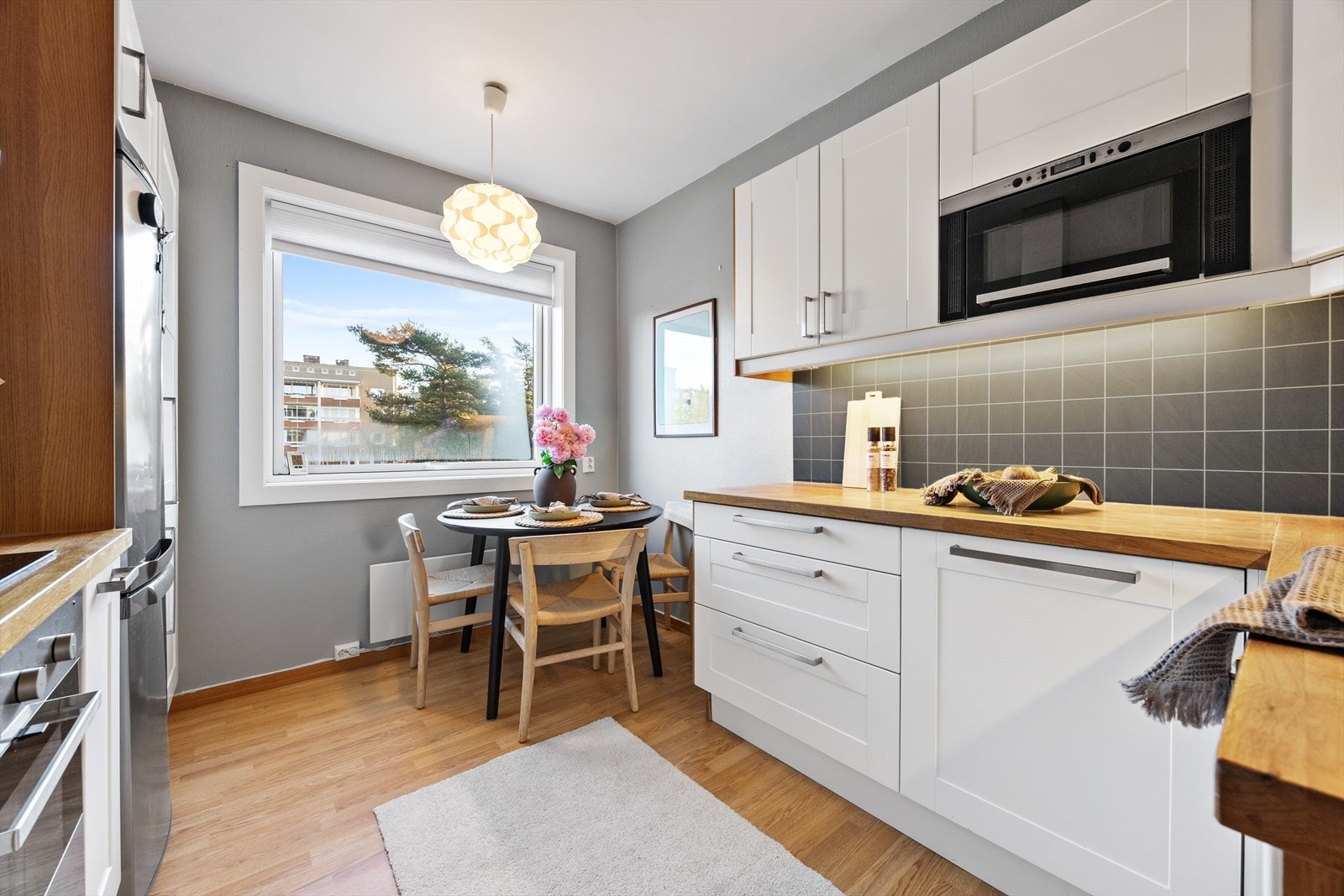 Lyst kjøkken fra 2009 med profilerte fronter, benkeplate i tre og plass til spisebord. Galleribilde