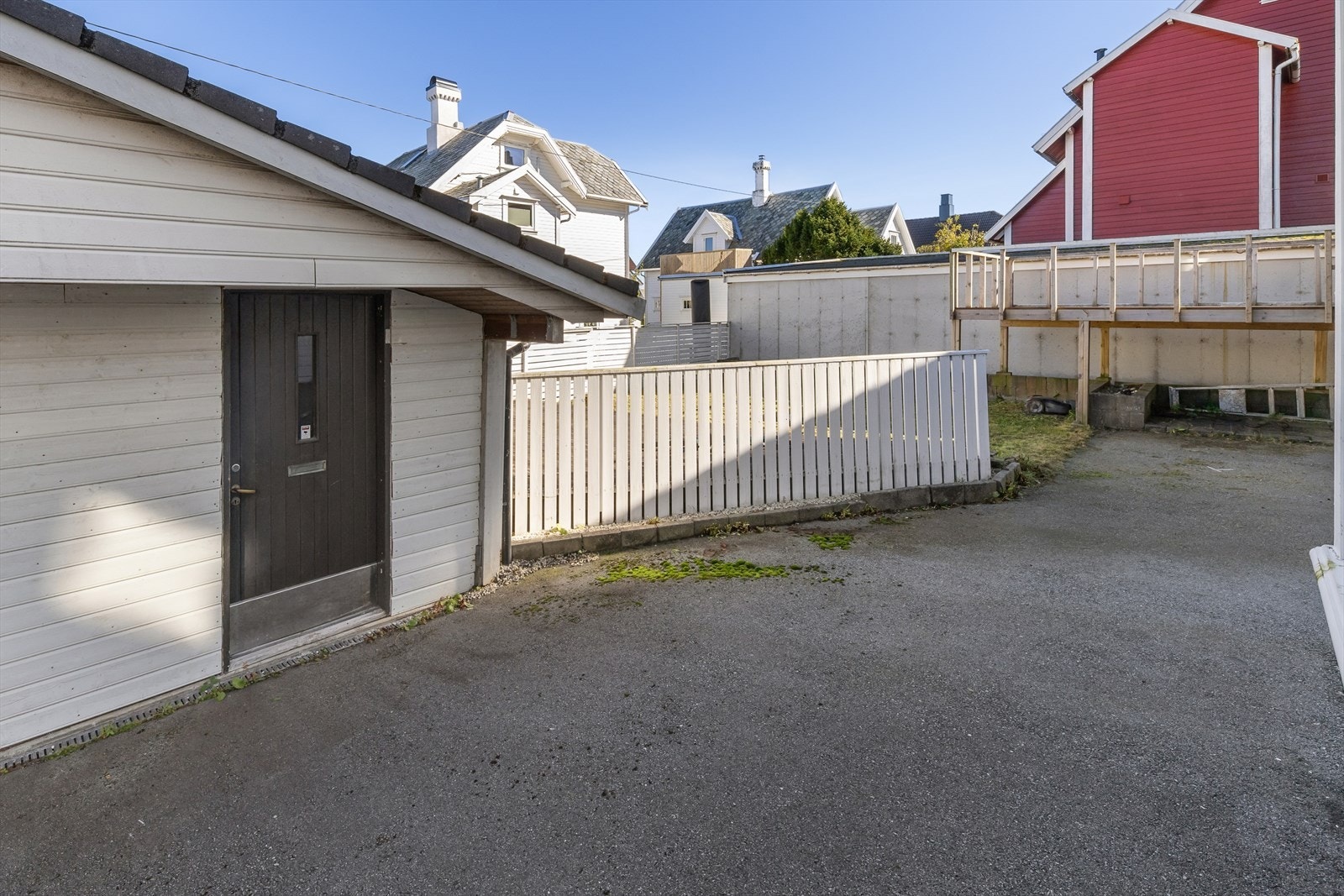 Felles asfaltert gårdsplass med både parkeringsmuligheter og boder. Galleribilde