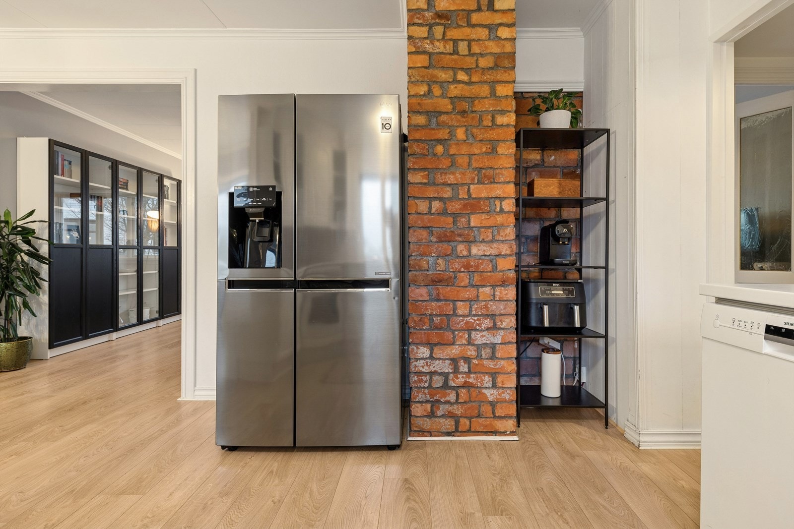 Kjøleskap og teglsteinsvegg gir kjøkkenet et robust preg og ekstra lagringsplass. Galleribilde