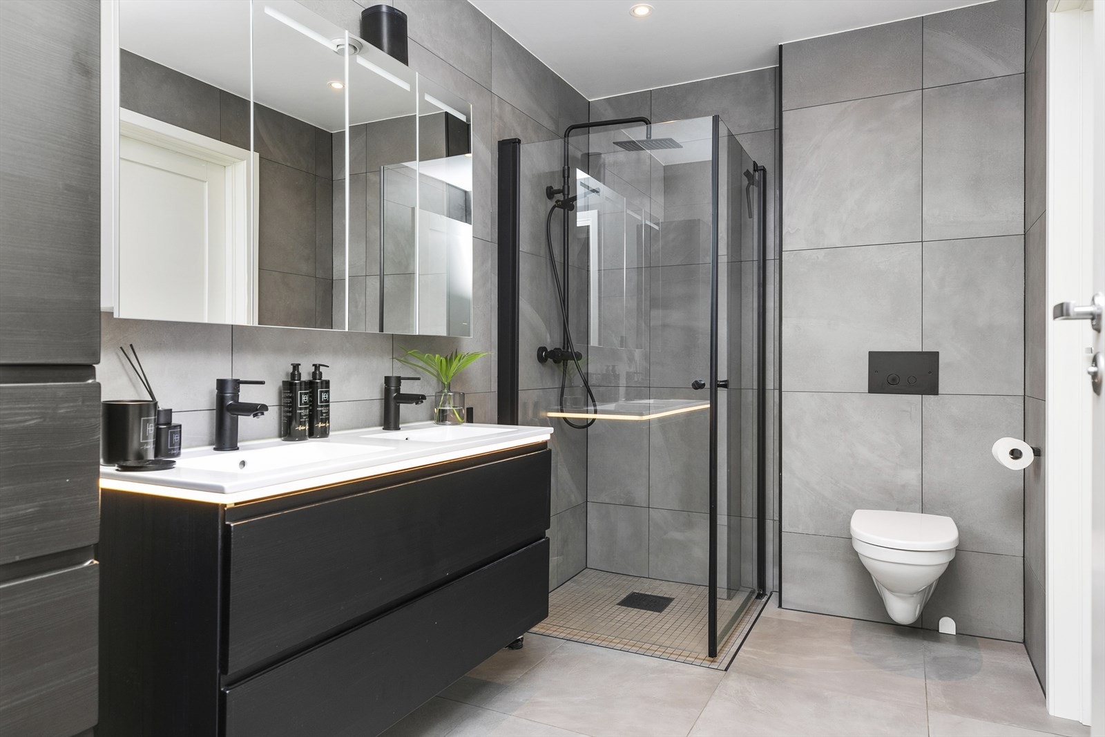 Stilrent, flislagt bad i første etasje med vegghengt toalett og dusjhjørne med svingbare glassdører. Galleribilde