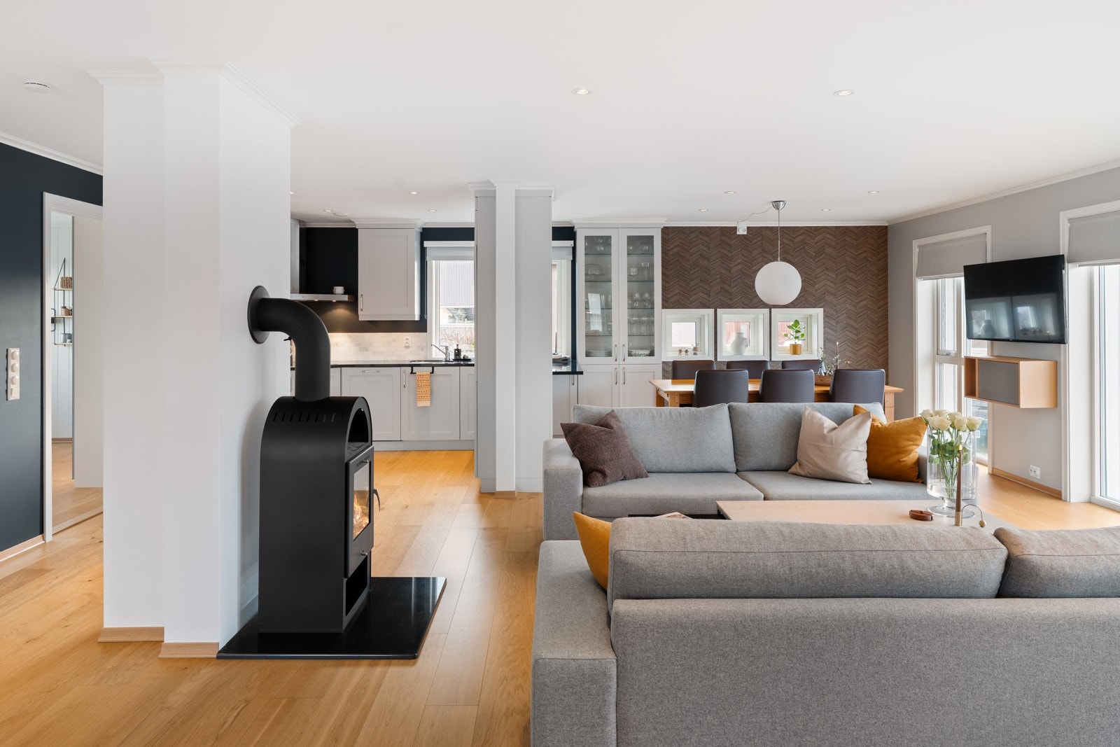 Lys og tiltalende stue med åpen løsning og en stilren vedovn som sørger for både varme og hygge på kalde vinterdager. Galleribilde