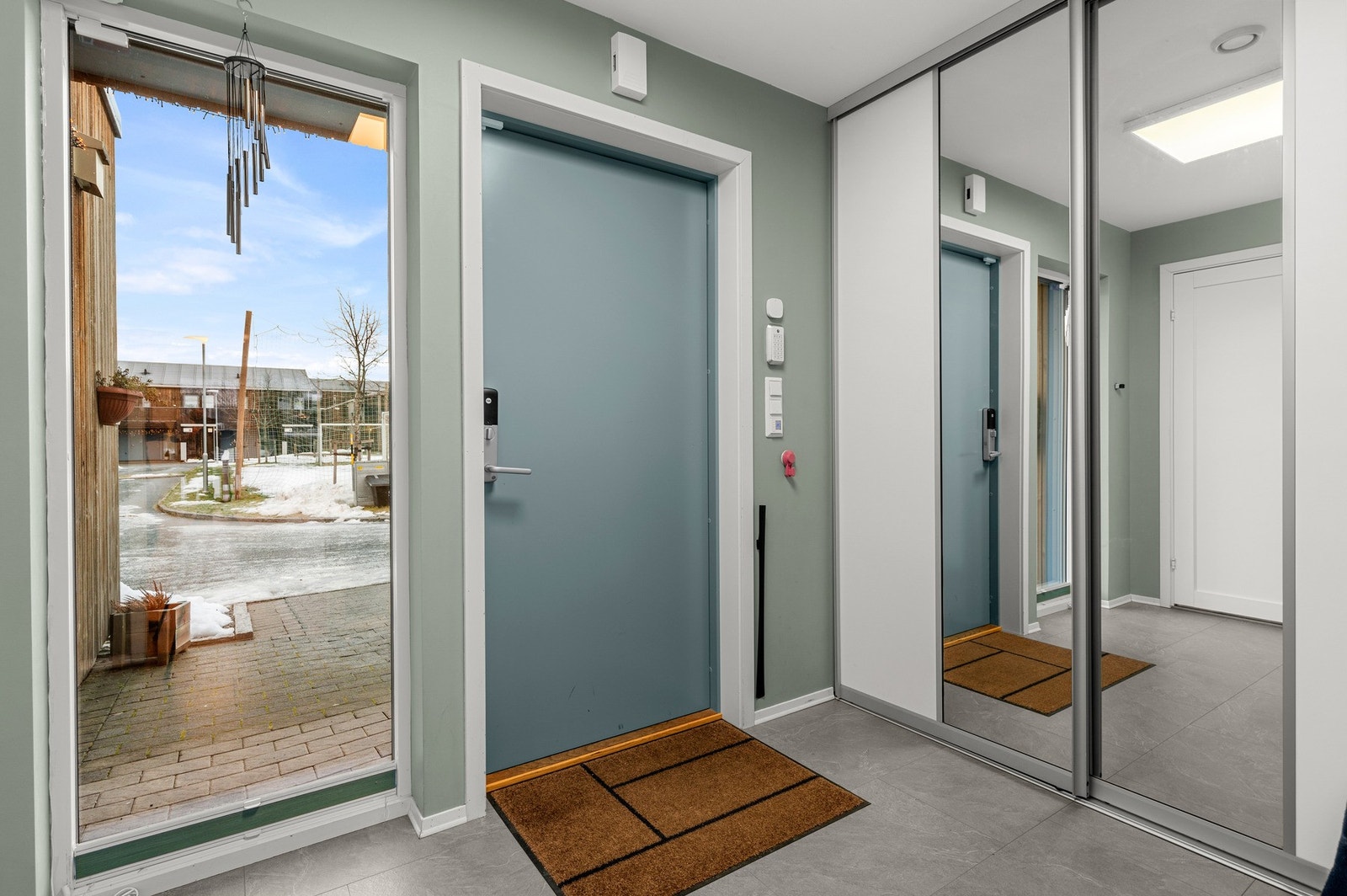 Praktisk entrè med skyvedørsgarderobe og dør inn til bad med toalett Galleribilde