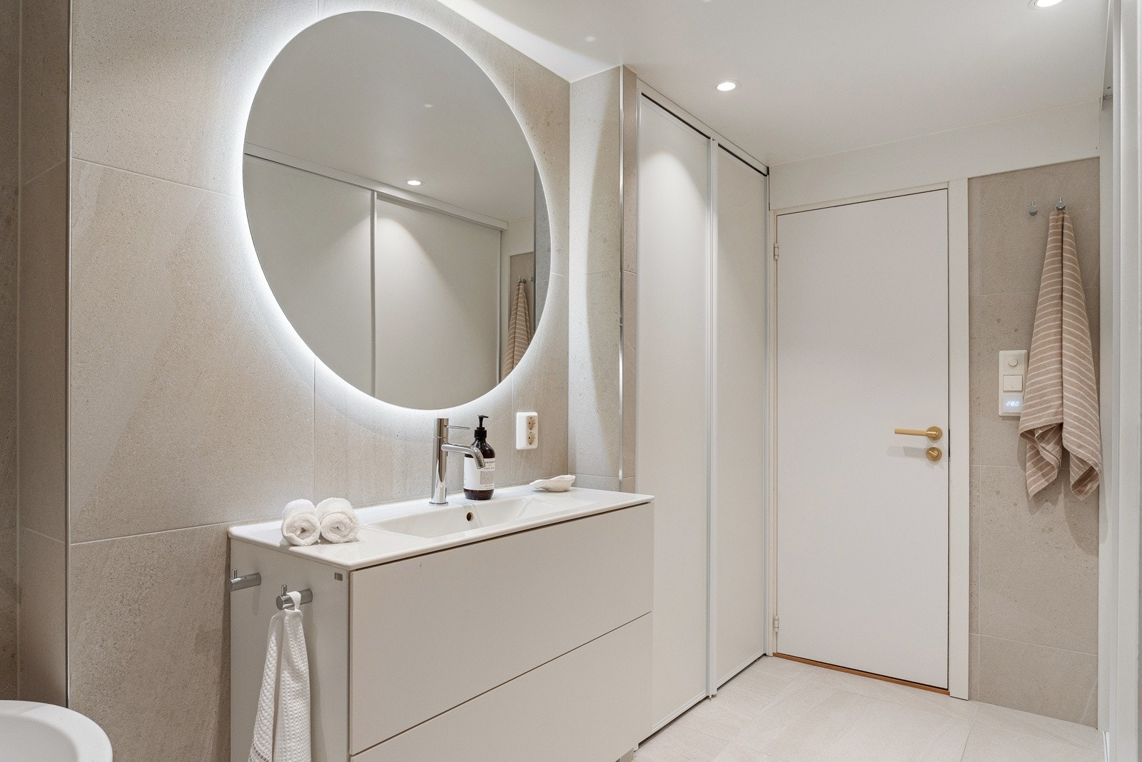Videre byr baderommet på servantskap, rundt speil med integrert belysning på vegg over servant. Galleribilde