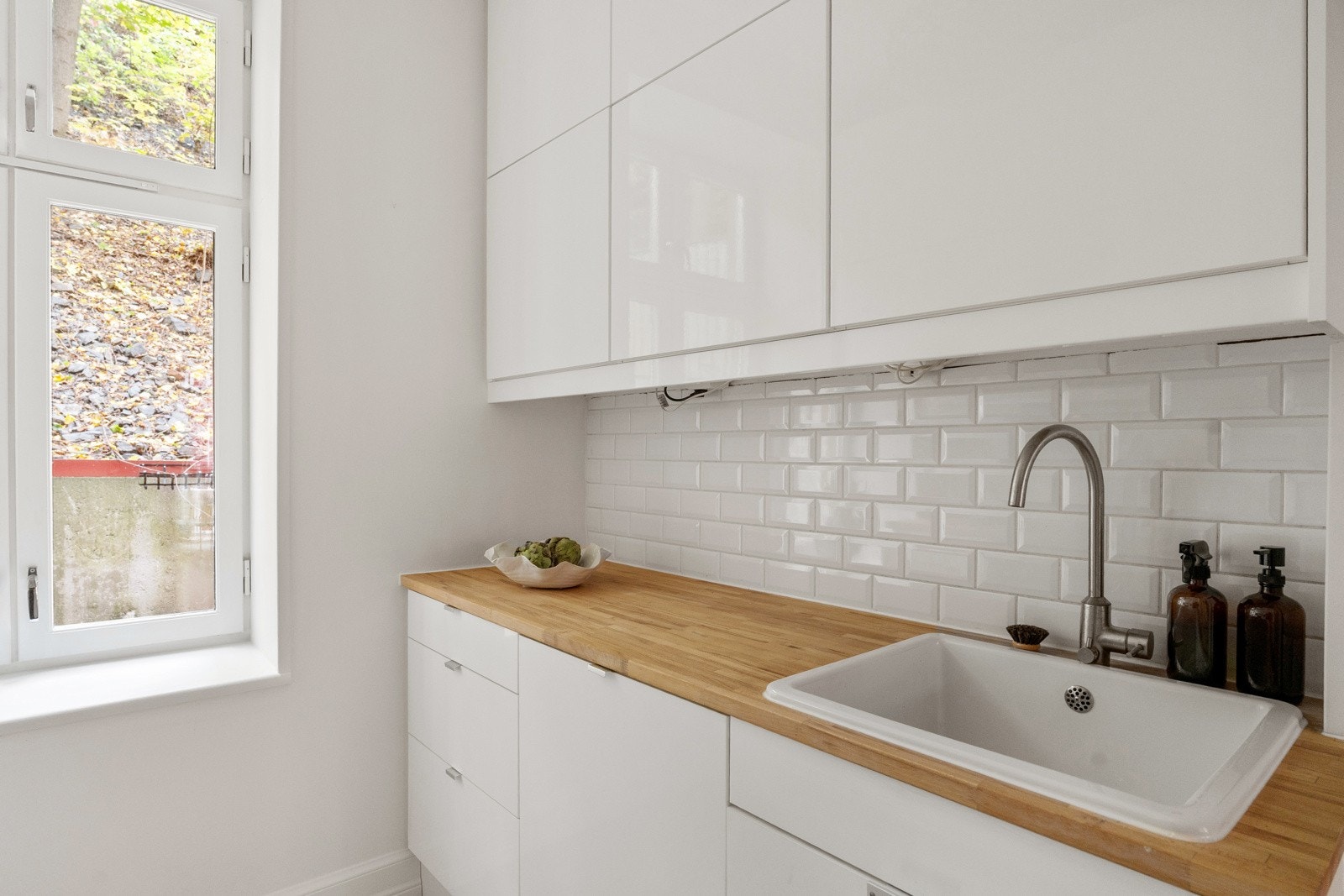 Belysning via downlights under overskap og fliser på vegg over benkeplaten. Galleribilde