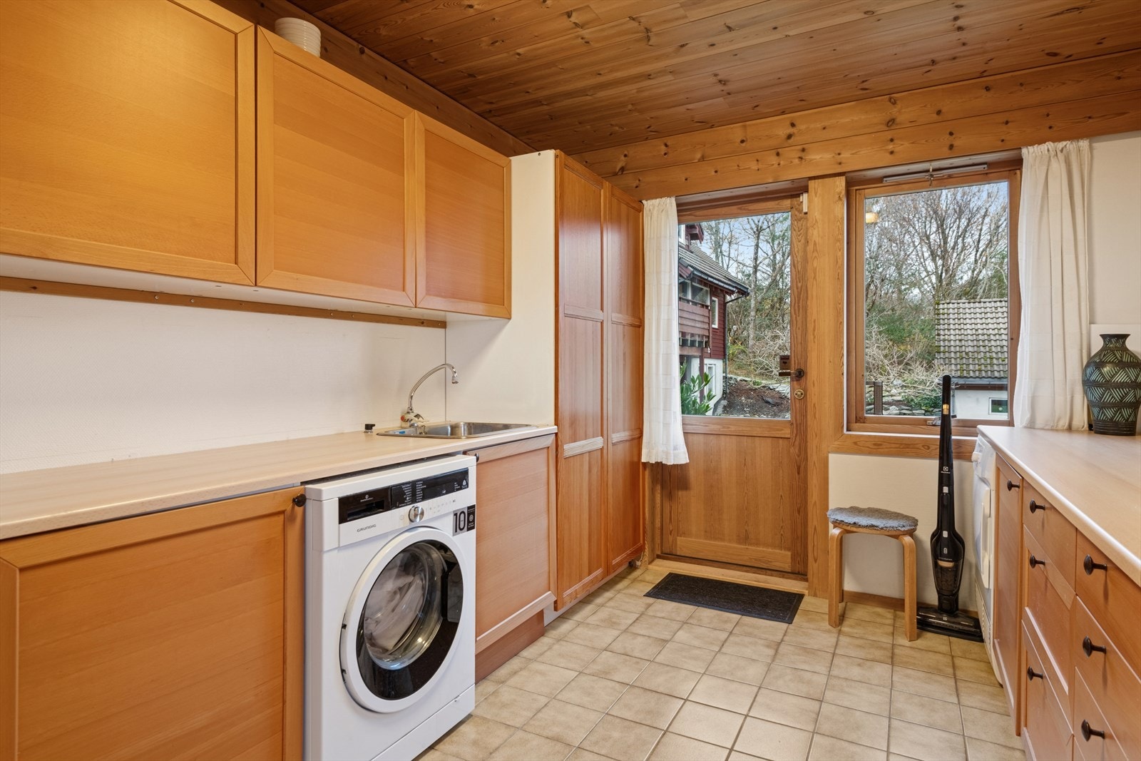 Vaskerommet har praktisk innredning med skap og benkeplate. Utgang til hagen. Galleribilde