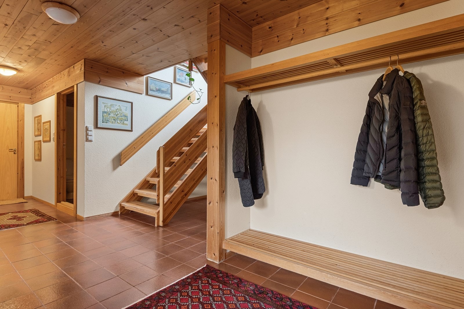 Flislagt gulv og lakkert tretrapp gir en solid og praktisk entré. Galleribilde