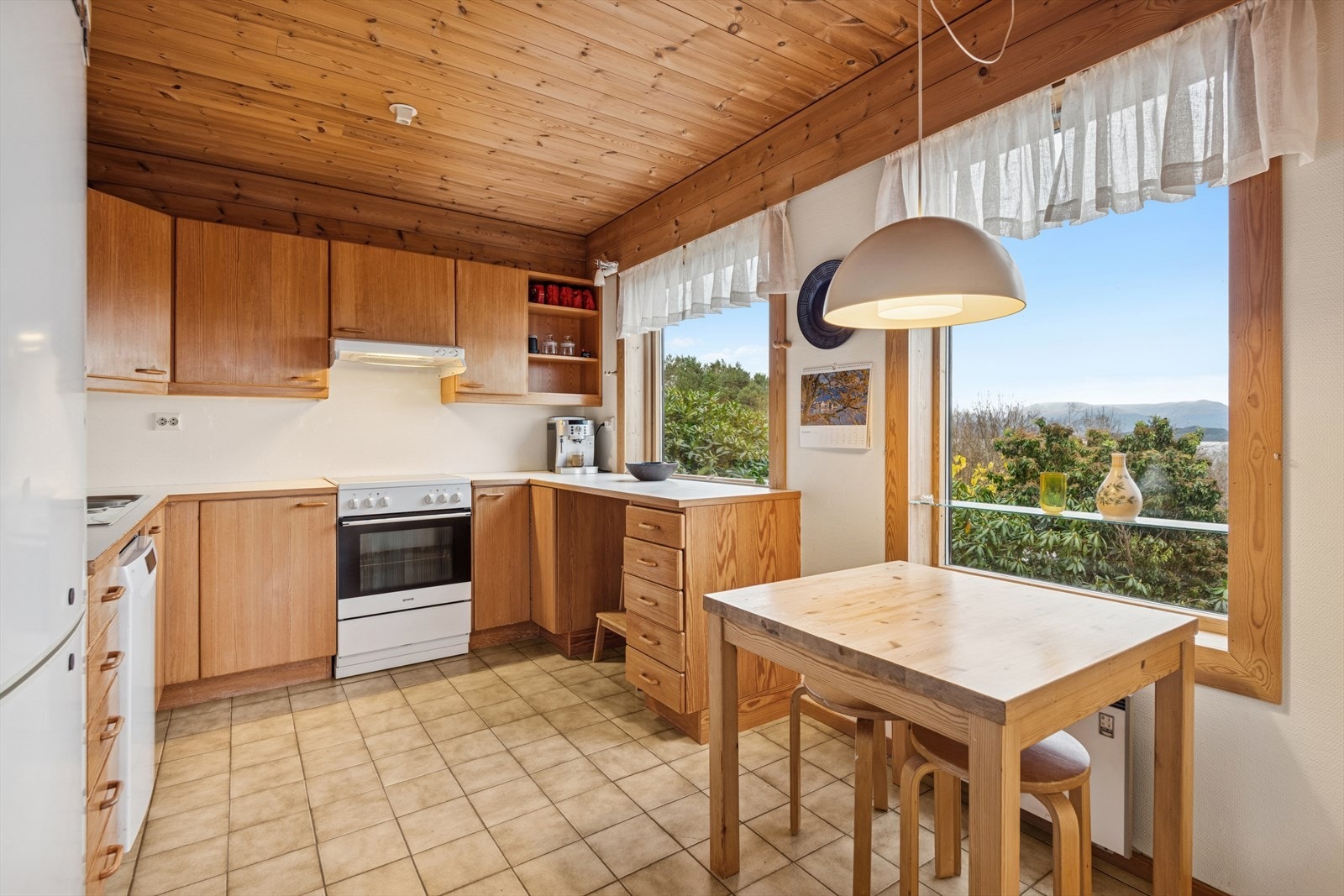 Store vinduer gir utsyn mot grøntområde og naturlig lys til spiseplassen. Galleribilde