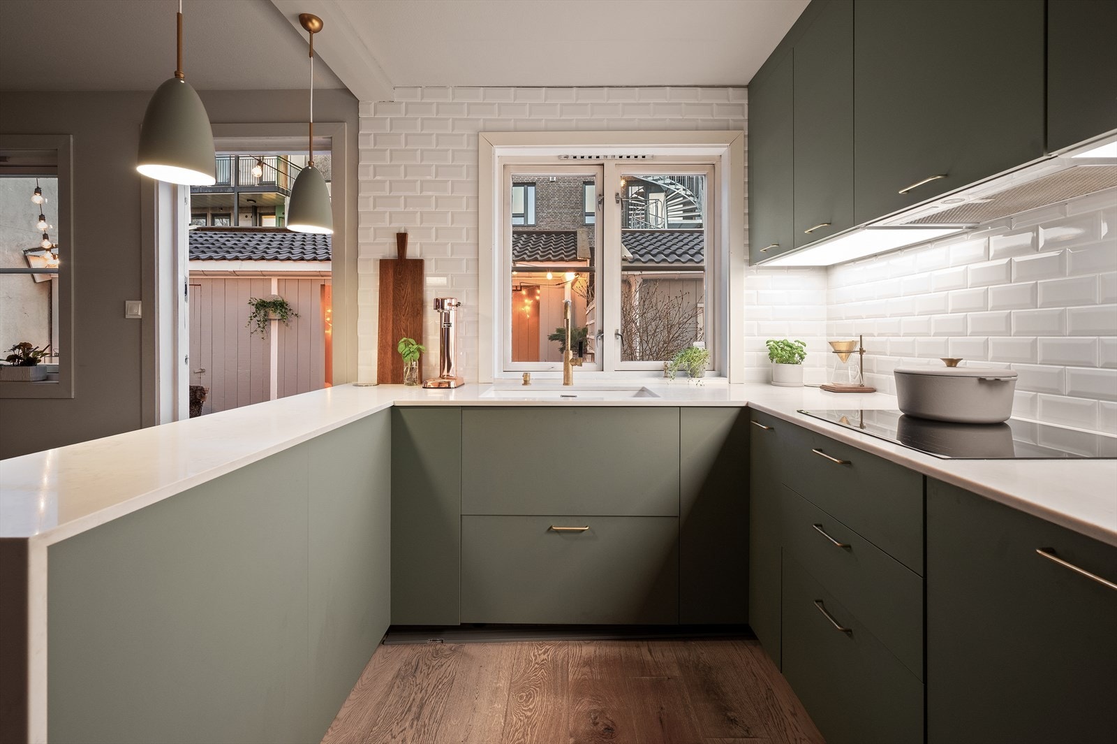 Benkeplaten i mineralkompositt med underlimt vaskekum, og veggflater mellom benkeplate og overskap er flislagt for et helhetlig og gjennomført uttrykk Galleribilde