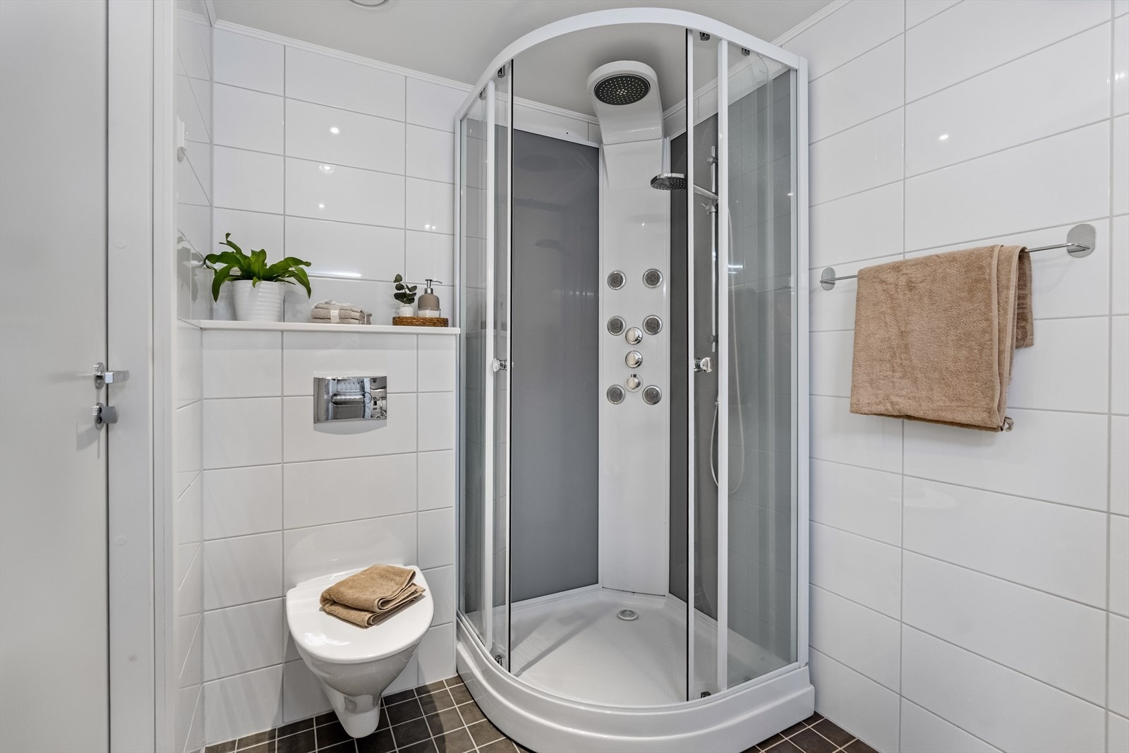 Rommet har servant, underskap med slette fronter, veggmontert toalett, dusjkabinett og opplegg for vaskemaskin. Galleribilde