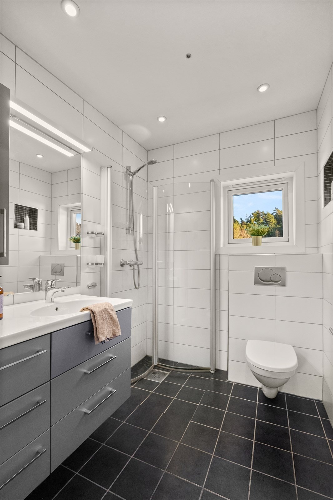 Delikat flislagt baderom (2012) med downlights i tak og behagelig gulvvarme. Justerbare dusjdører er satt inn for å utnytte plassen maksimalt. Galleribilde