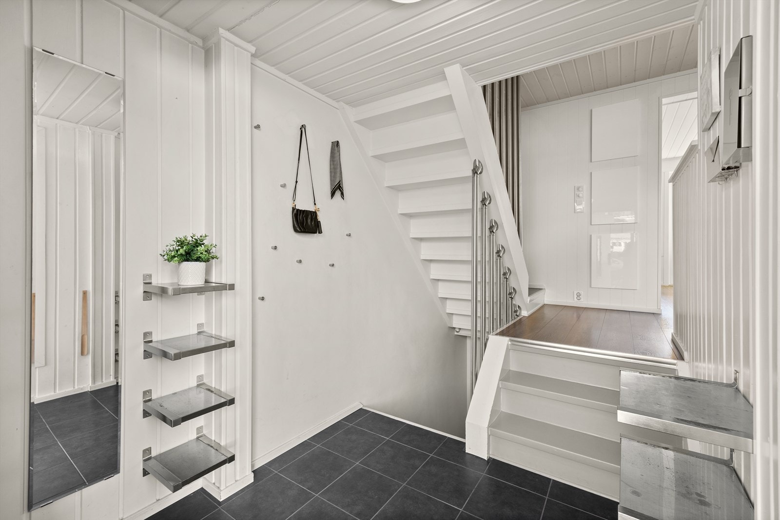 Fra boligens overbygde inngangsparti ønskes man velkommen inn i en flislagt entré med varmekabler. Galleribilde