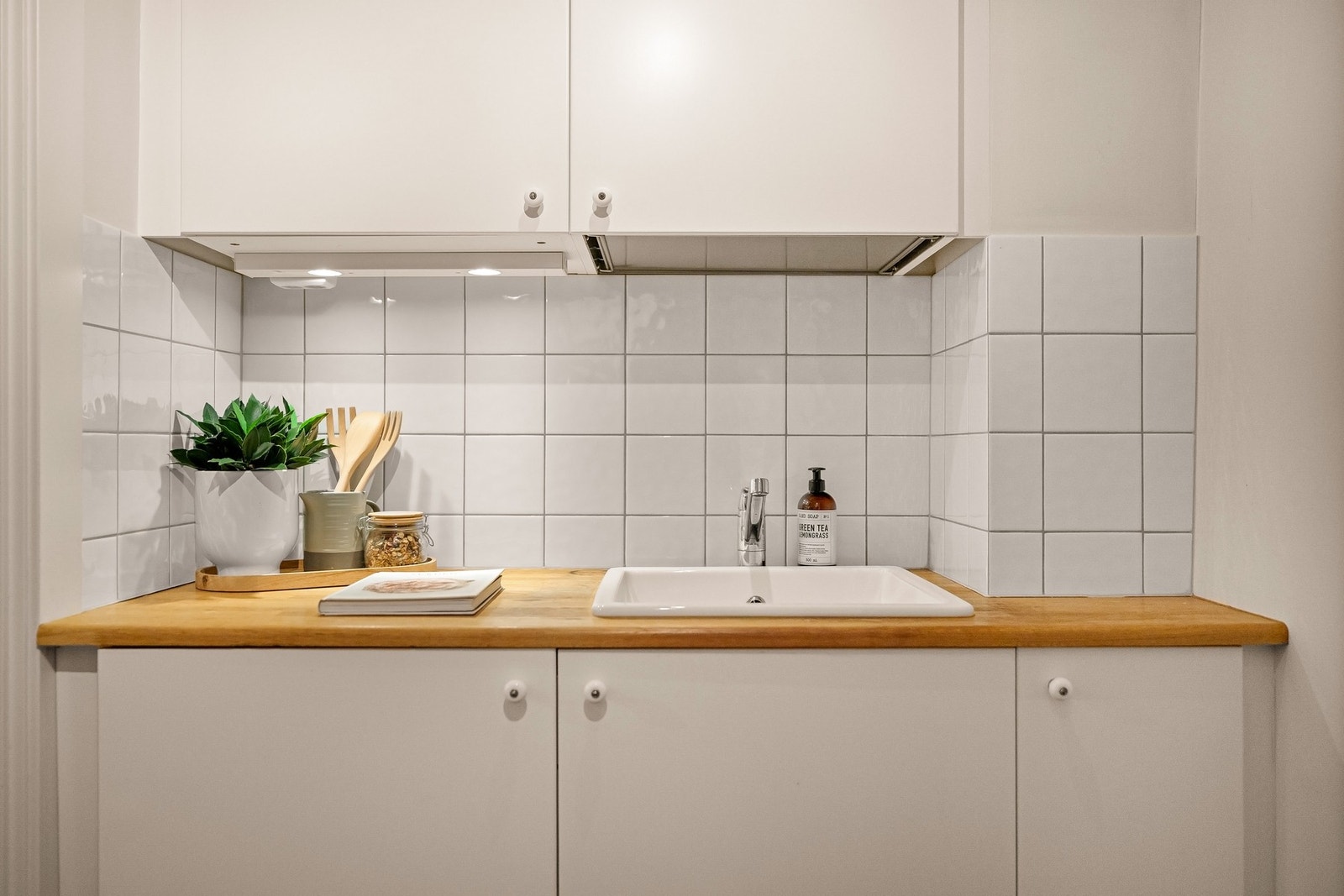 Pent kjøkken med lyse fronter og benkeplate i tre. Galleribilde